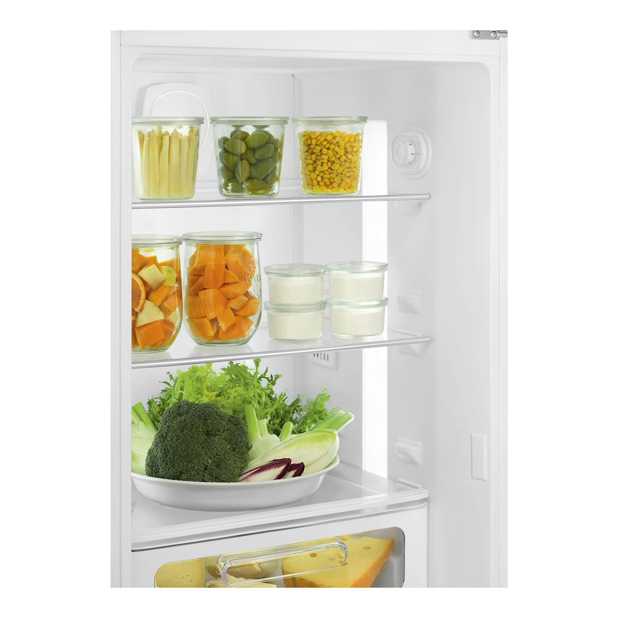 Interior frontal de frigorífico blanco con estantes, tarros con verduras y recipientes con yogur.