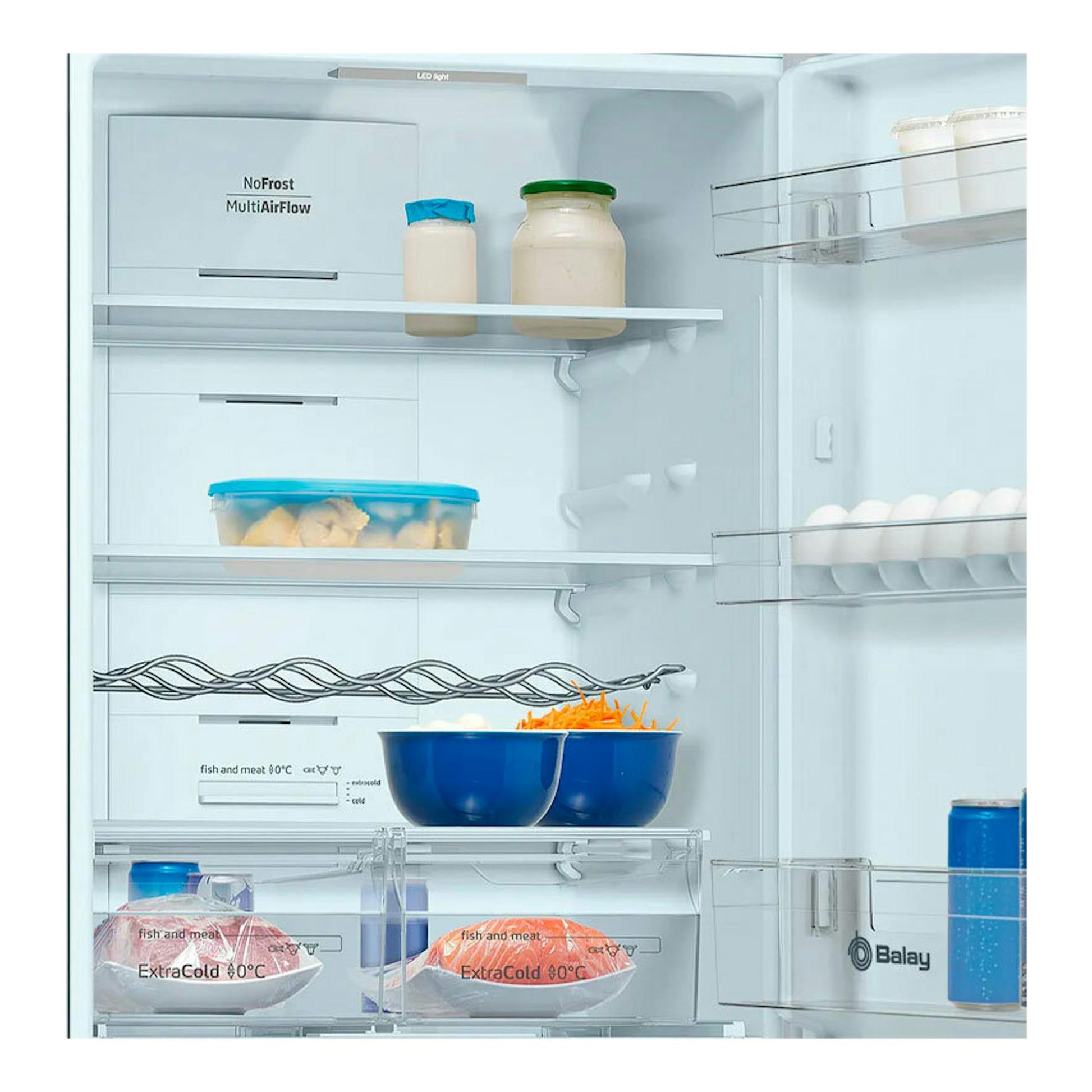 Vista frontal del interior de un frigorífico combi Balay, con estantes, cajones transparentes y alimentos.