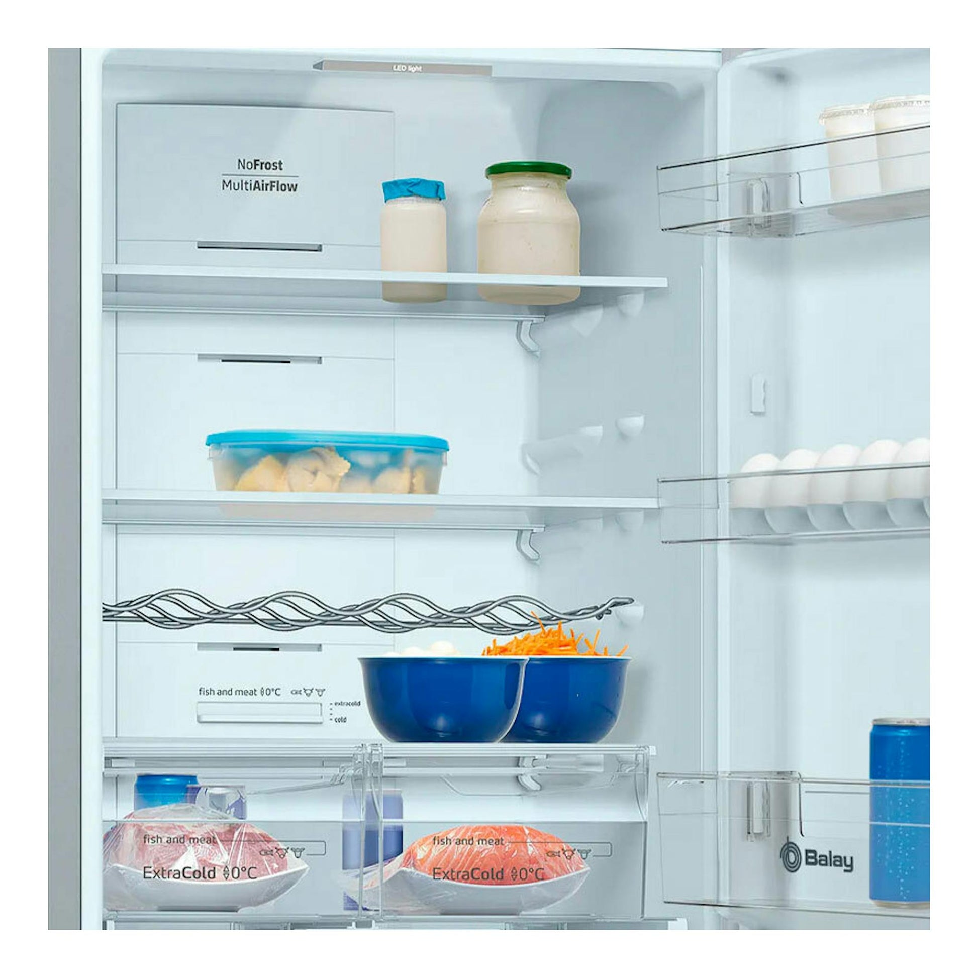 Interior de frigorífico combi Balay 3KFD565BI blanco, con estantes, cajones y alimentos.