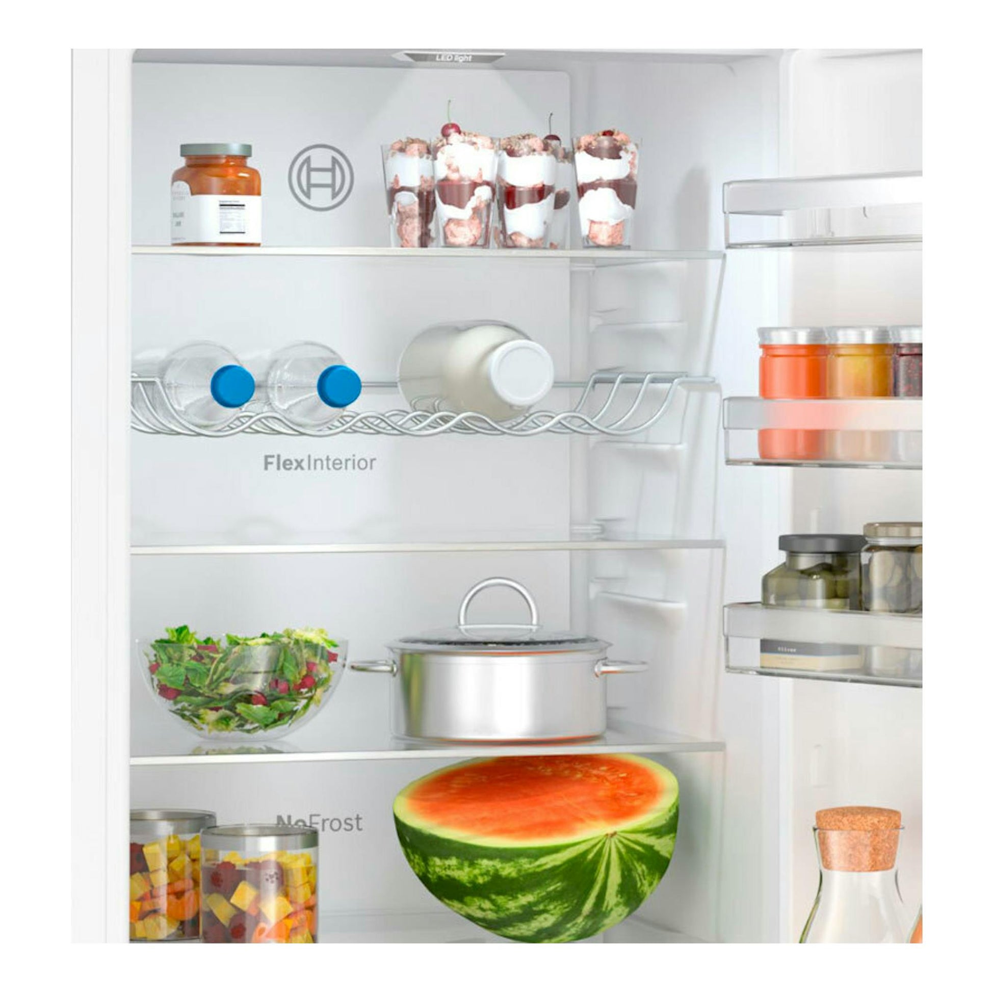 Vista frontal del interior de un frigorífico Bosch KGN392WCF blanco con estantes, tarros, ensalada, olla y media sandía.