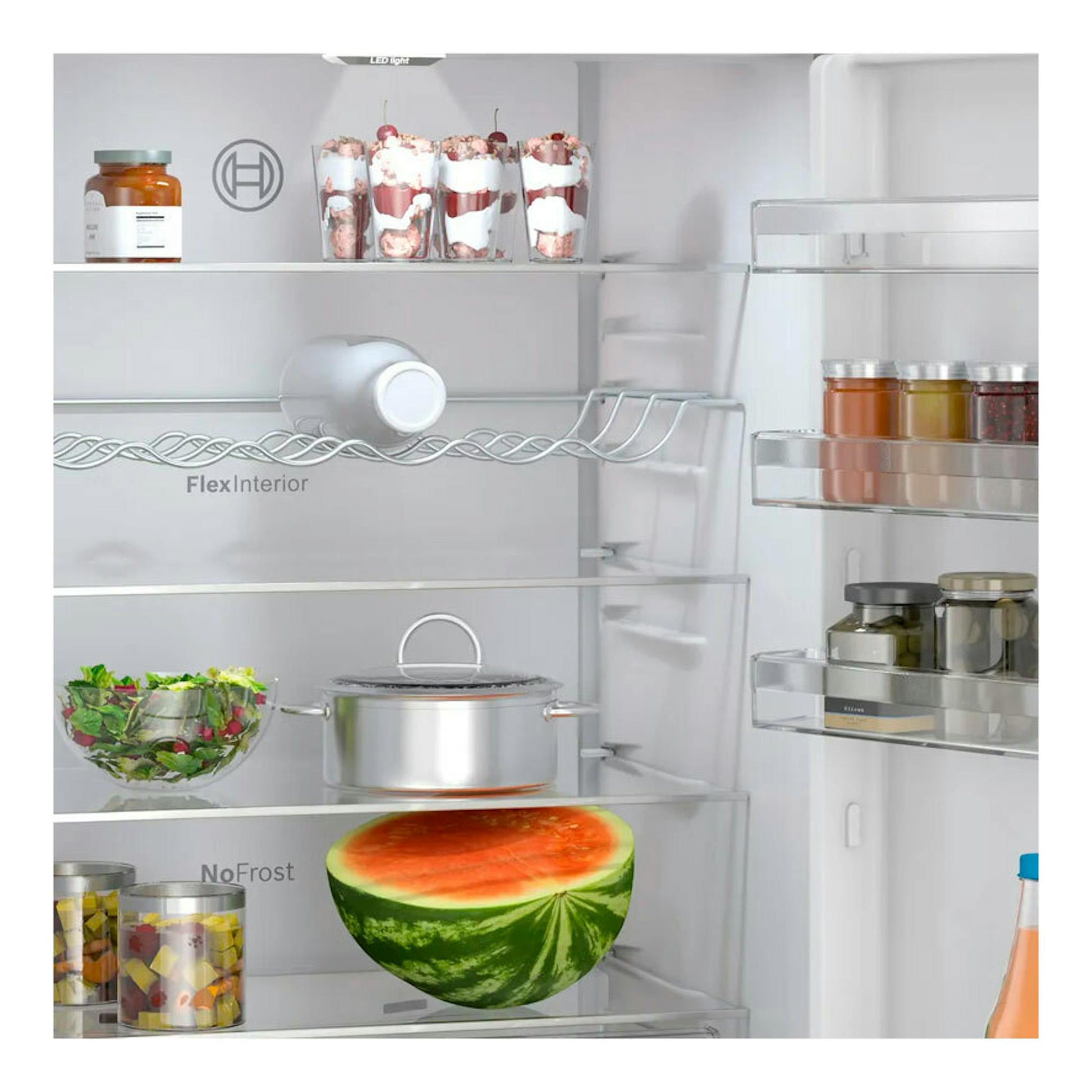 Vista frontal del interior de un frigorífico Bosch KGN49OCAF Inox con estantes de cristal y alimentos.