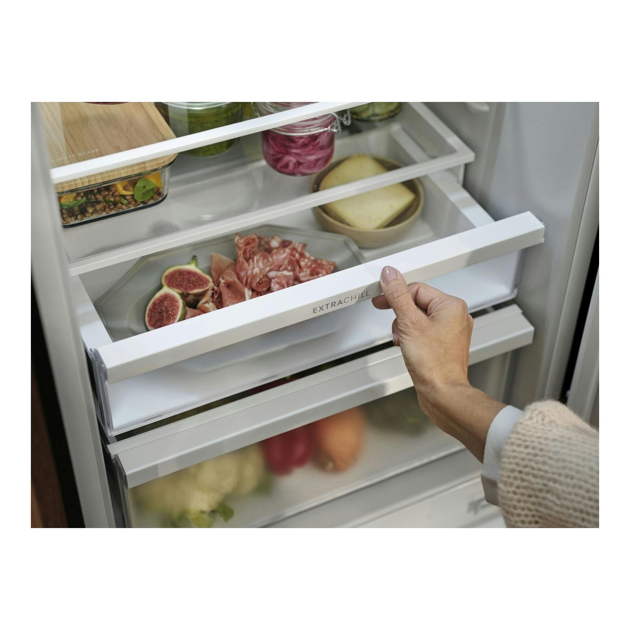 Frigorífico combi Electrolux ENA7CE18S1, interior blanco con cajones transparentes y una mano abriendo uno.