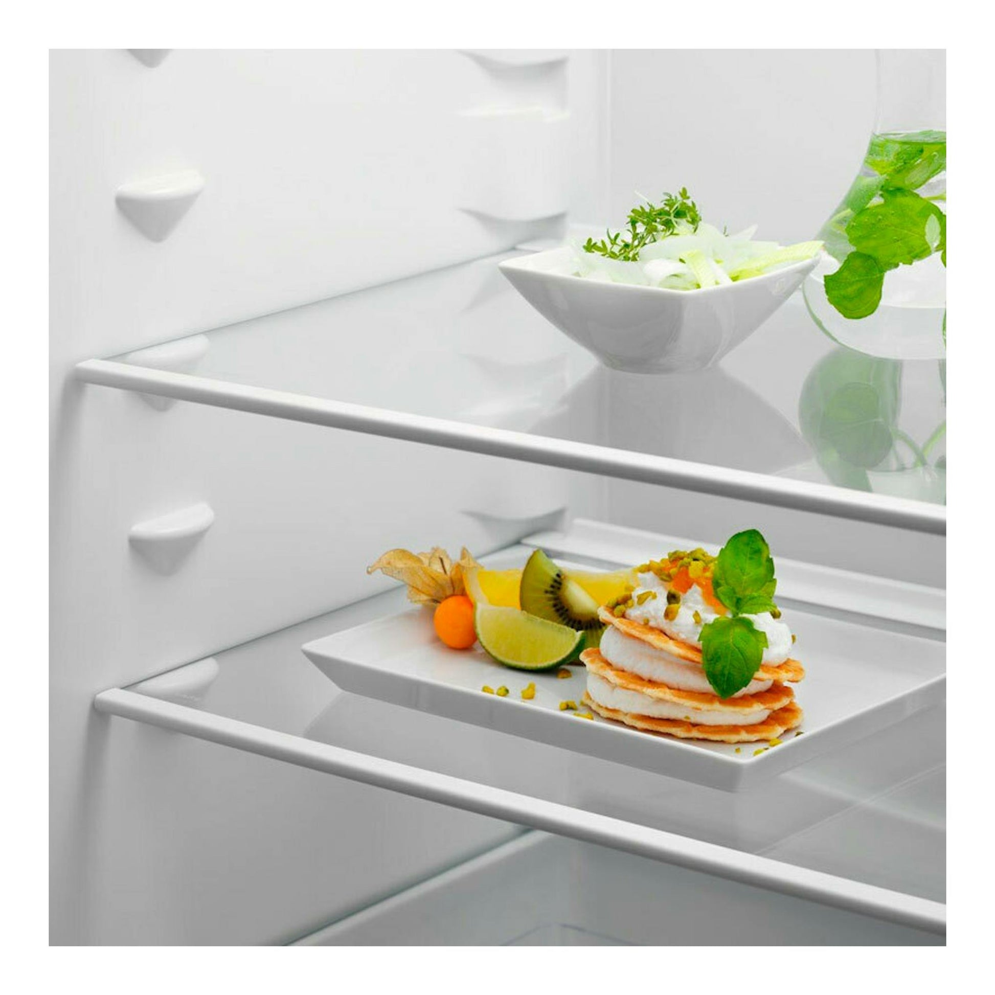 Interior de frigorífico combi integrable Electrolux ENT6NE18S, con baldas de vidrio y bandejas blancas con fruta.