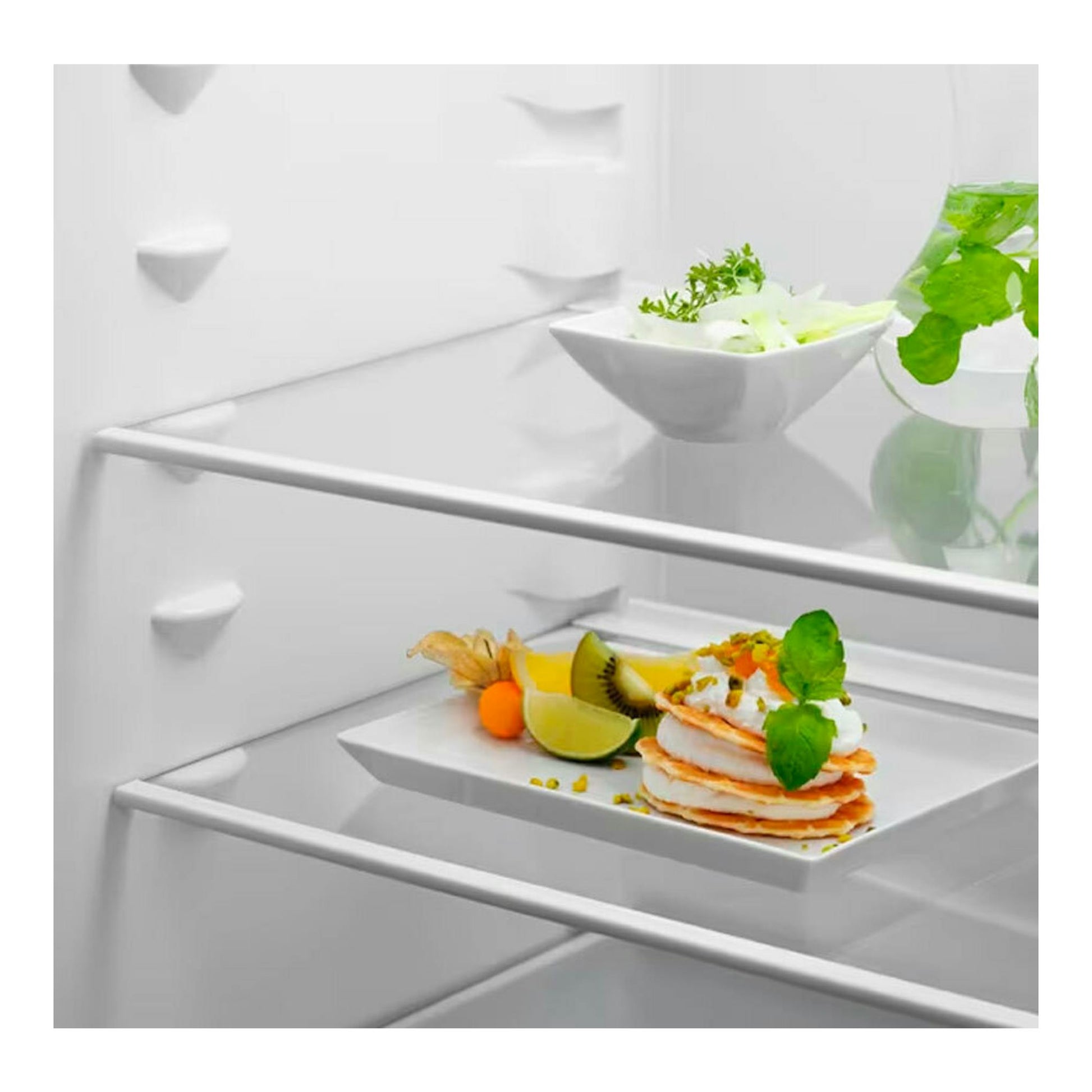 Interior de frigorífico combi integrable Electrolux LNS5LE18S, vista frontal, con estantes blancos y platos de comida.
