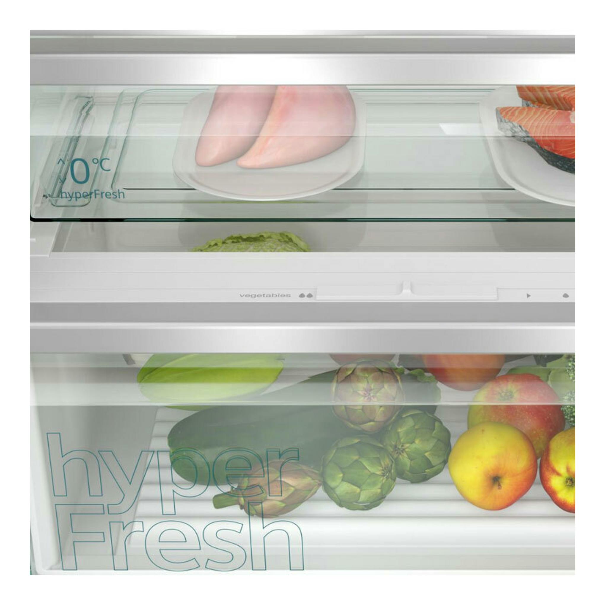 Vista frontal del interior de un frigorífico combi integrable Siemens KB96NVFE0 con cajón HyperFresh y alimentos.