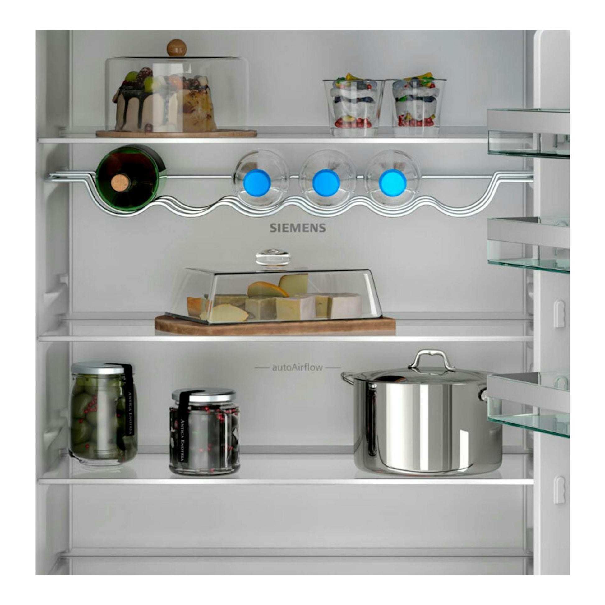 Vista frontal del interior de un frigorífico combi integrable Siemens KB96NVSE0 con baldas de cristal y alimentos.