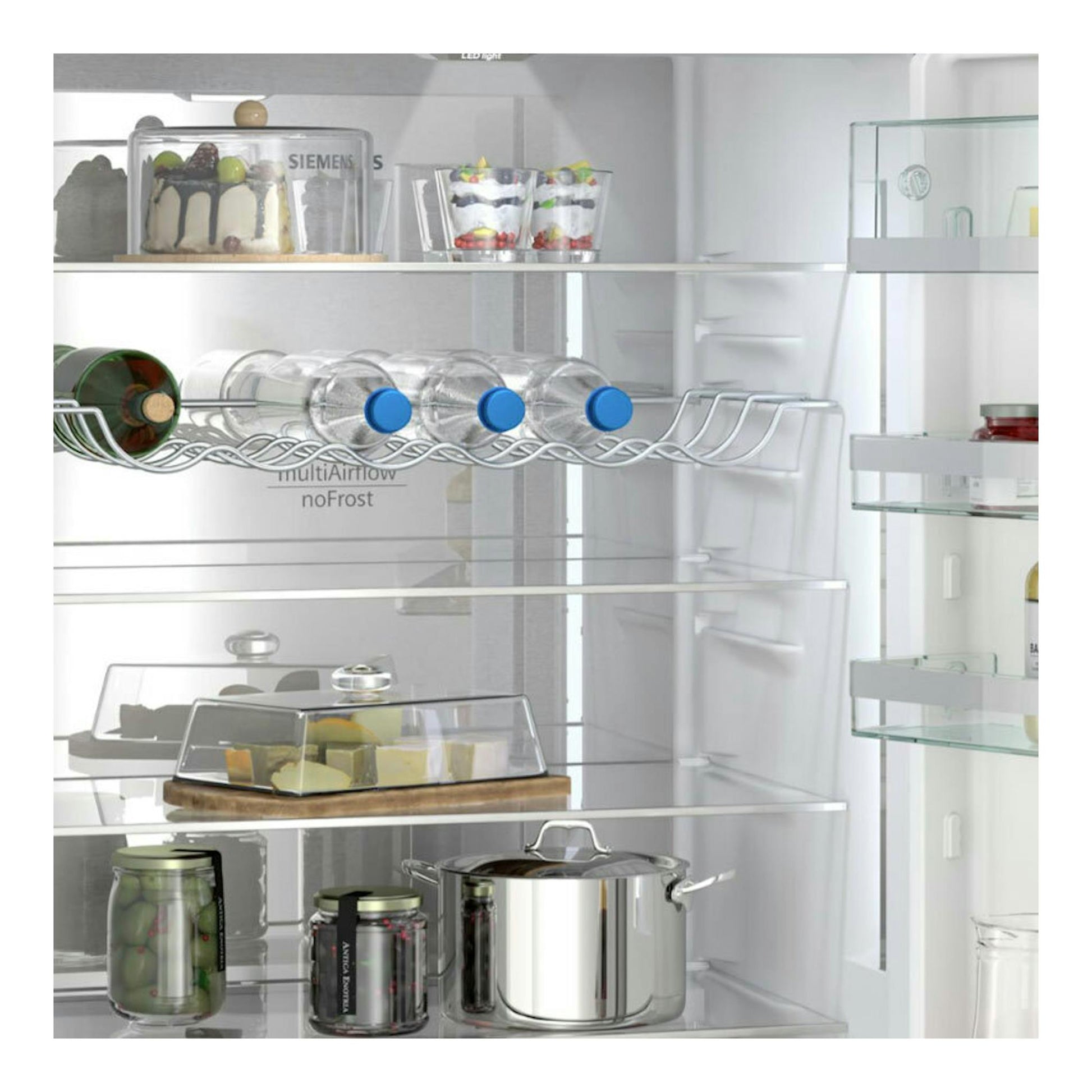 Interior frontal de frigorífico Siemens Inox con baldas de cristal, botellero y recipientes.