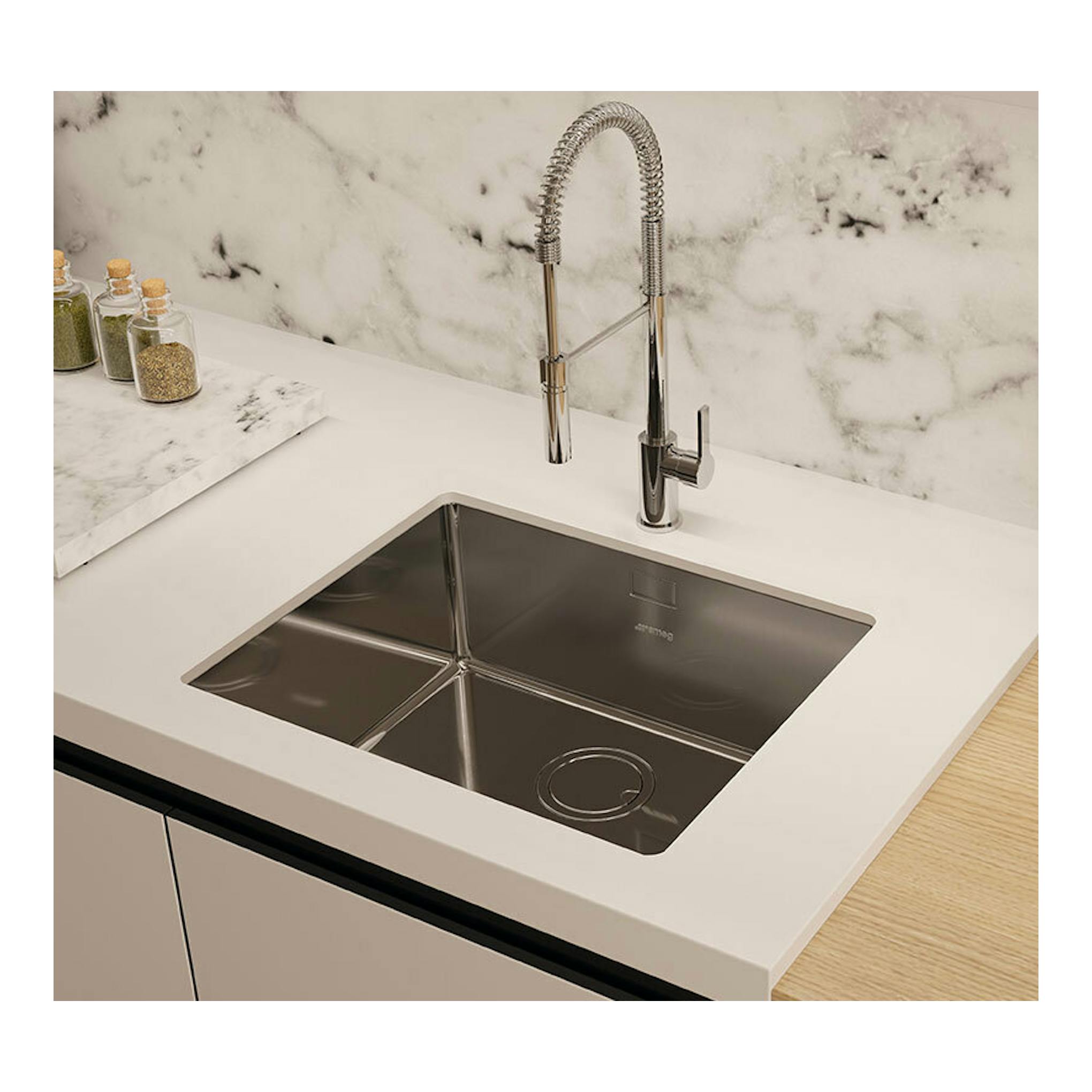 Grifo Smeg MID5CR cromado, vista frontal-oblícu a sobre fregadero de acero inoxidable en encimera blanca.