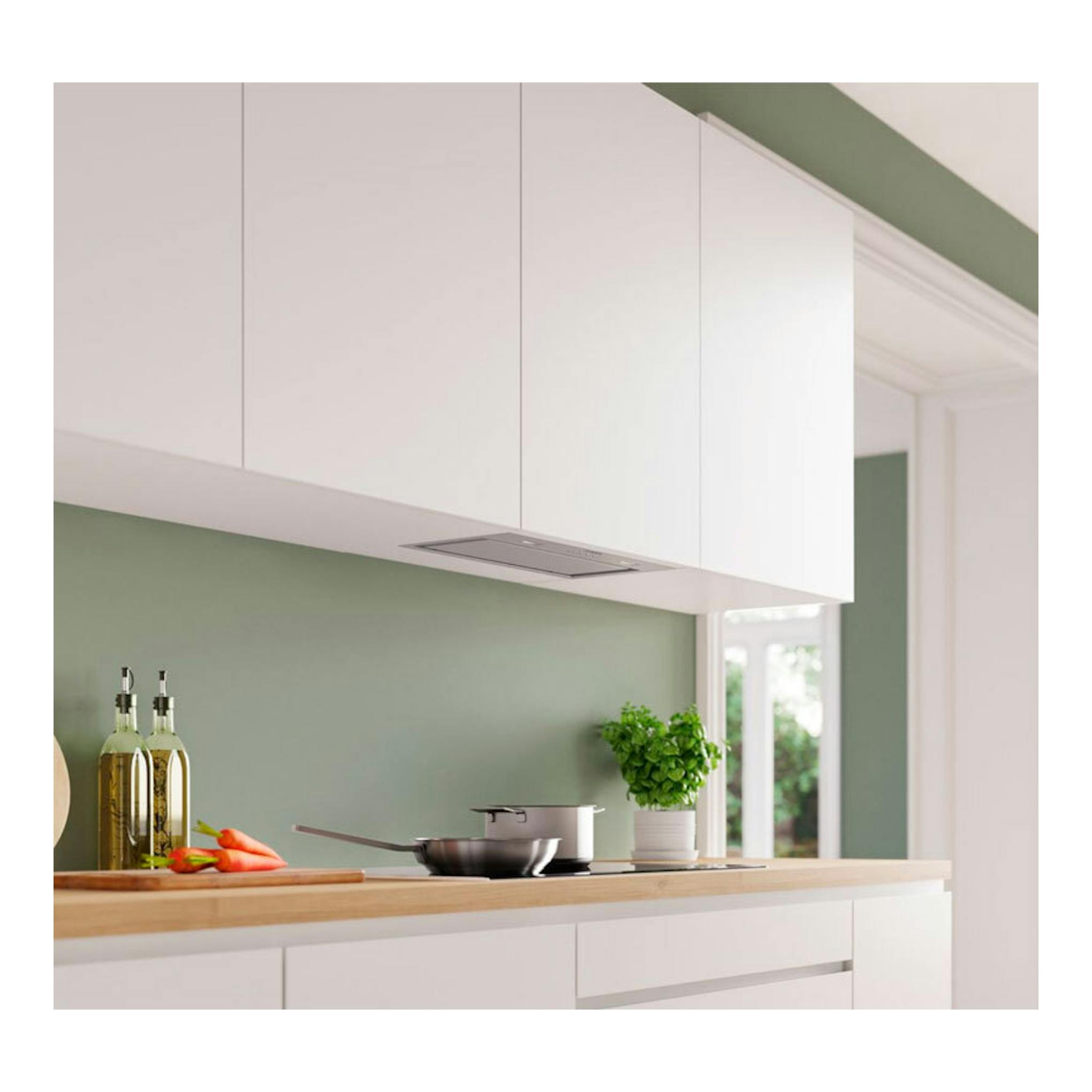 Grupo filtrante Bosch DLN56AC50 inox integrado bajo mueble en cocina blanca, vista frontal.