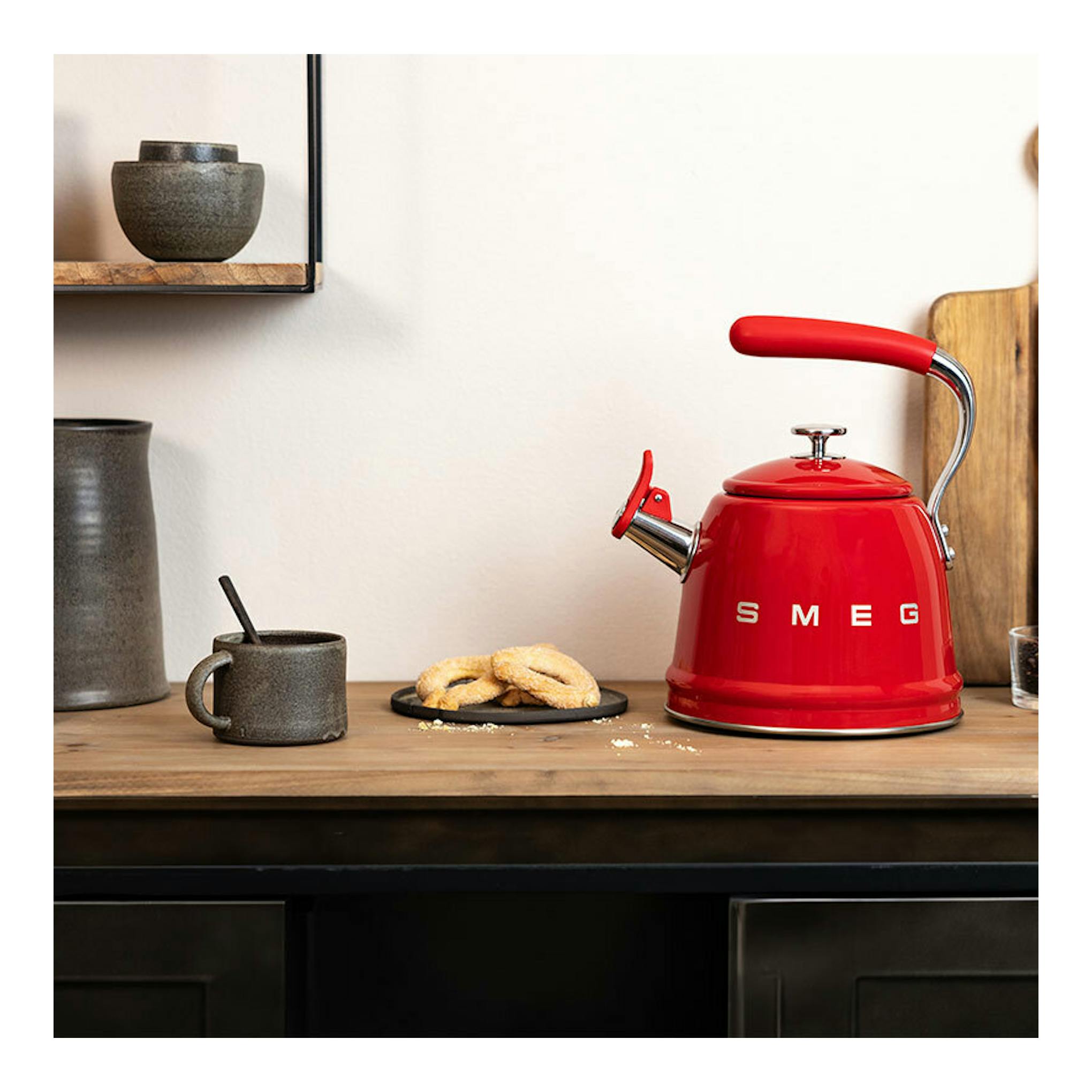Hervidor silbante Smeg WKF01RD rojo, vista frontal, sobre encimera de madera.