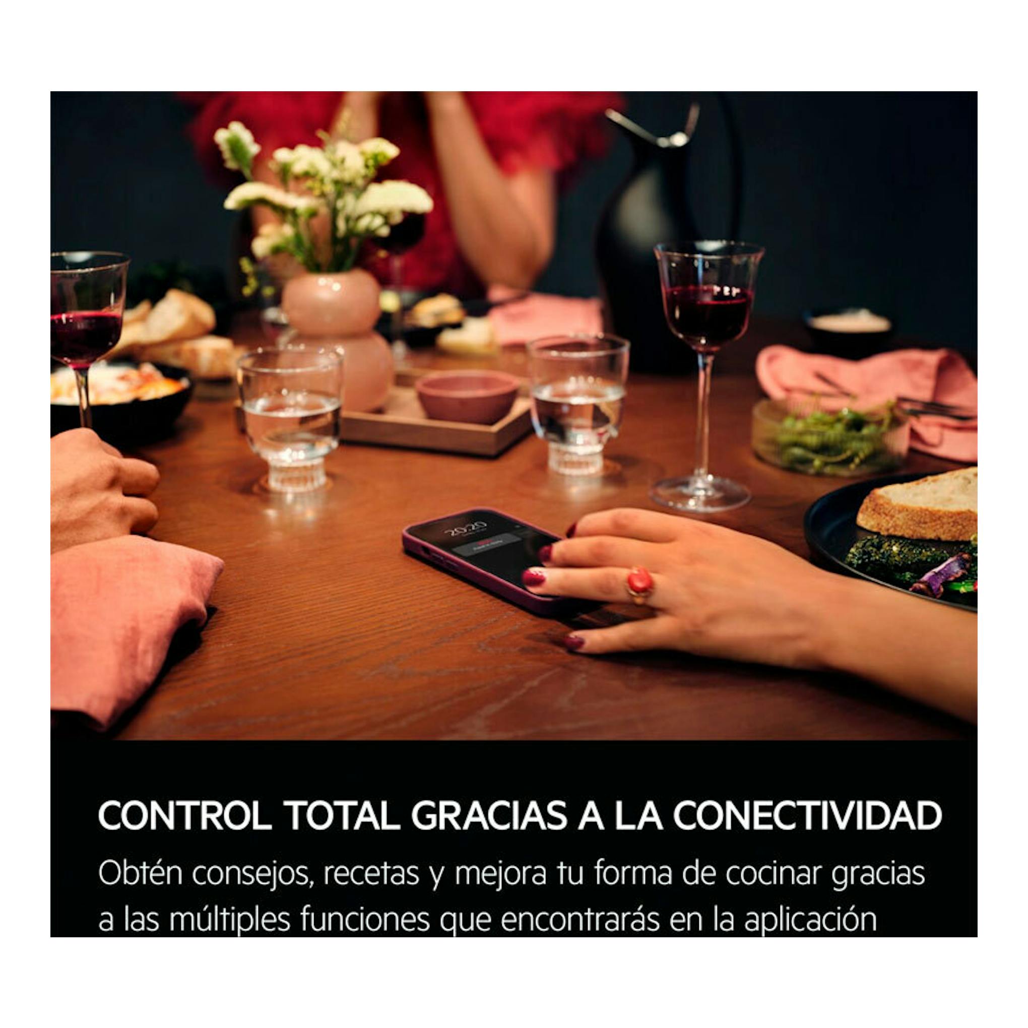 Mesa con cena y un móvil en primer plano; texto sobre conectividad de horno AEG OR6PB51WSB.