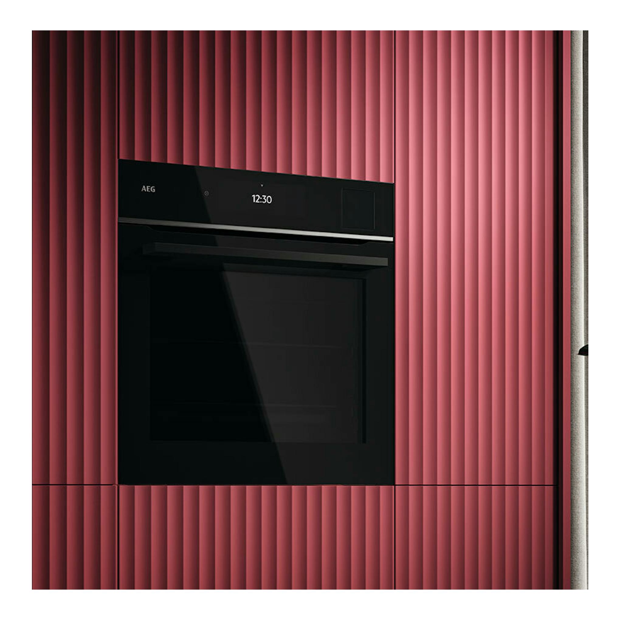 AEG TP9SB831AB, horno empotrado de cristal negro, vista frontal, con display 12:30, en mueble rosa.