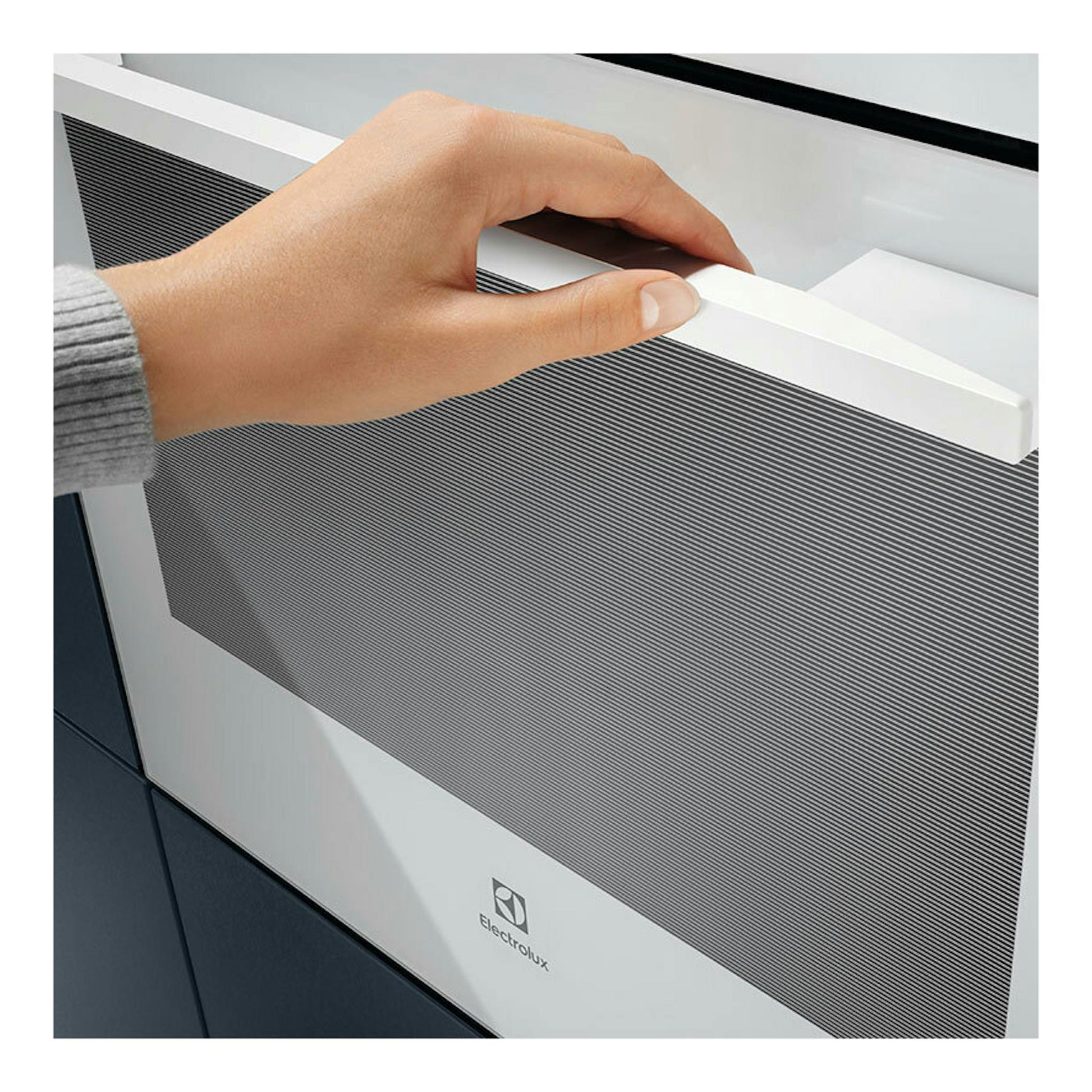 Horno Electrolux CKB101W blanco, vista frontal parcial, con una mano en el tirador.