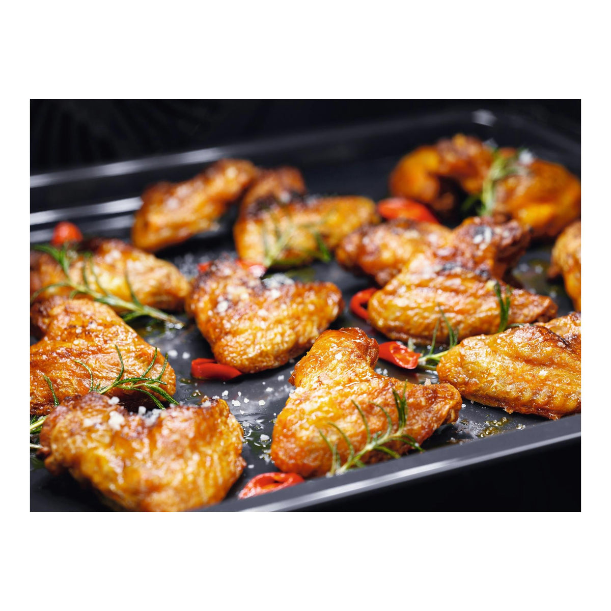 Horno Electrolux EOF3H40BX, vista interior con alitas de pollo doradas en bandeja negra.