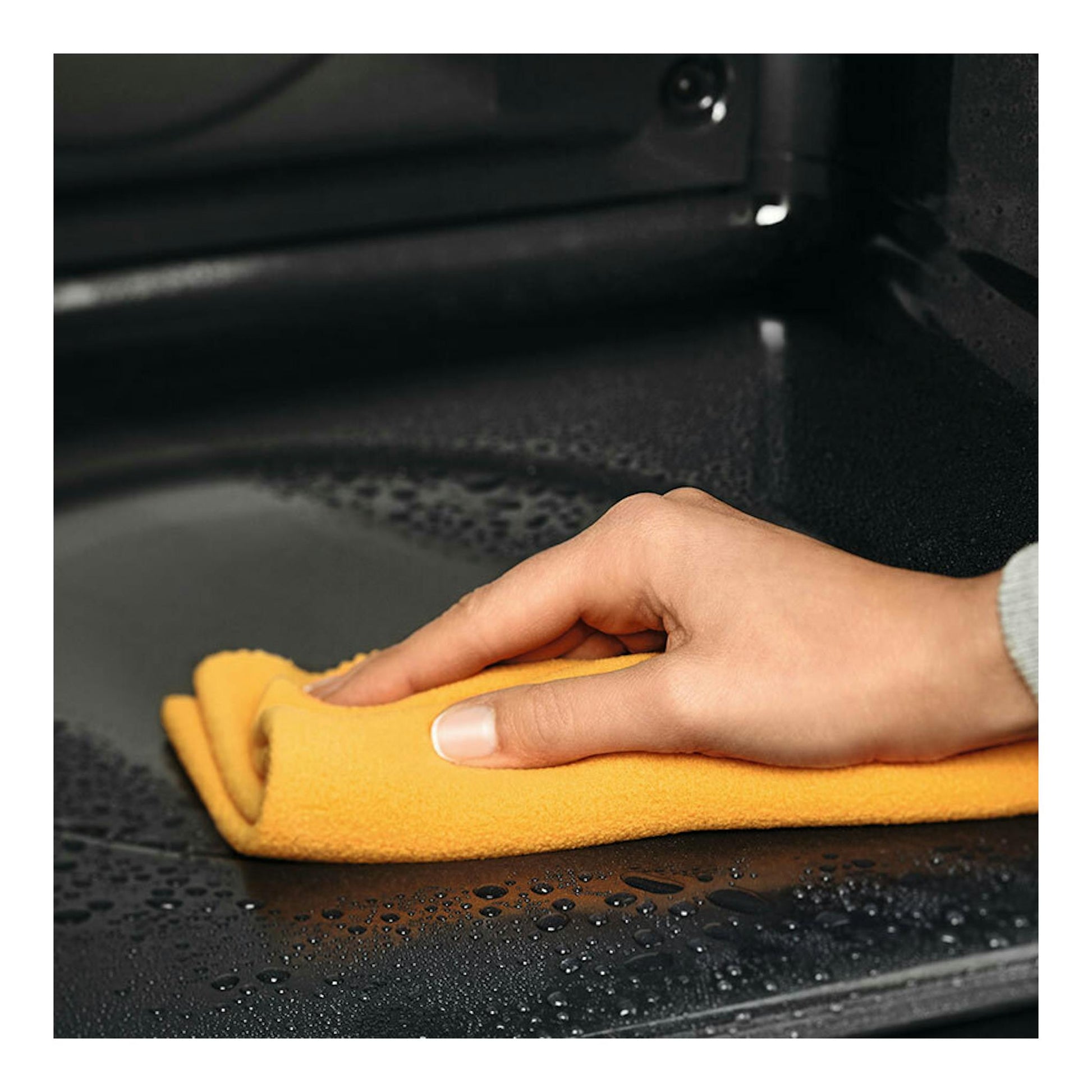Interior de horno Electrolux OEF5H50BK blanco, con una mano limpiando con un paño amarillo.