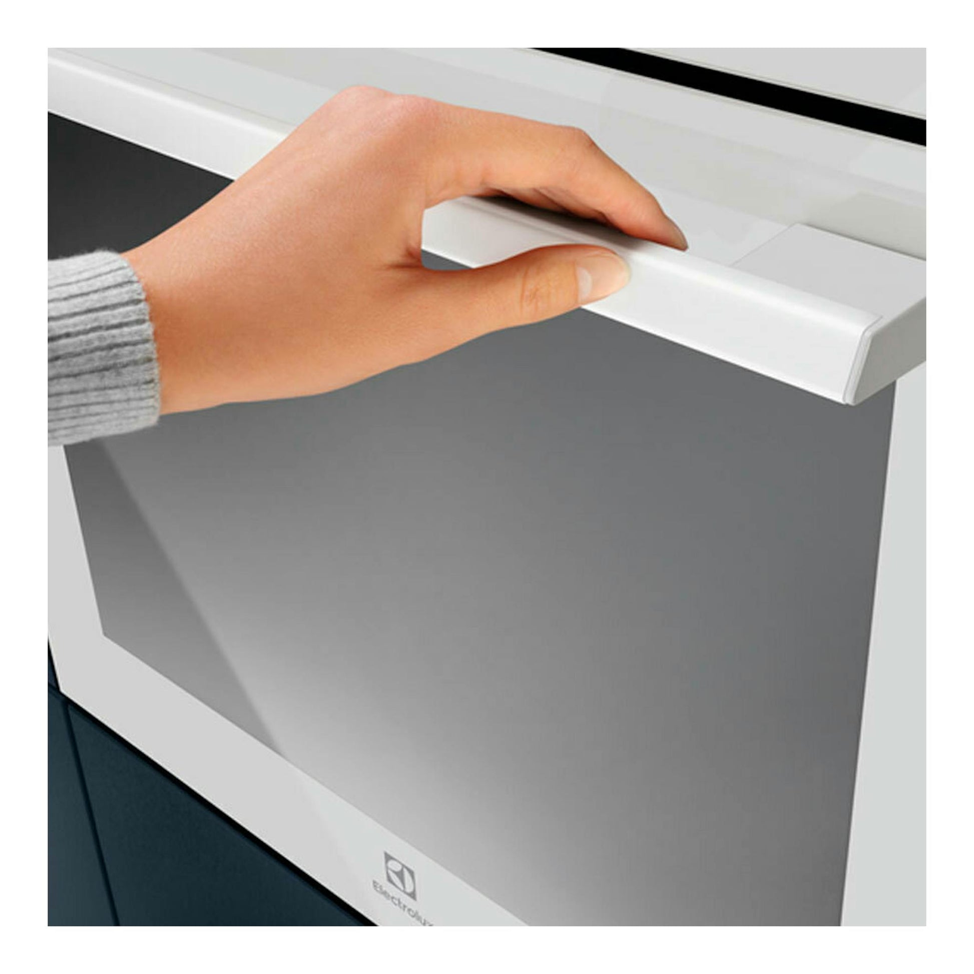 Primer plano frontal de horno Electrolux OEF5H50V blanco, con una mano abriendo la puerta.