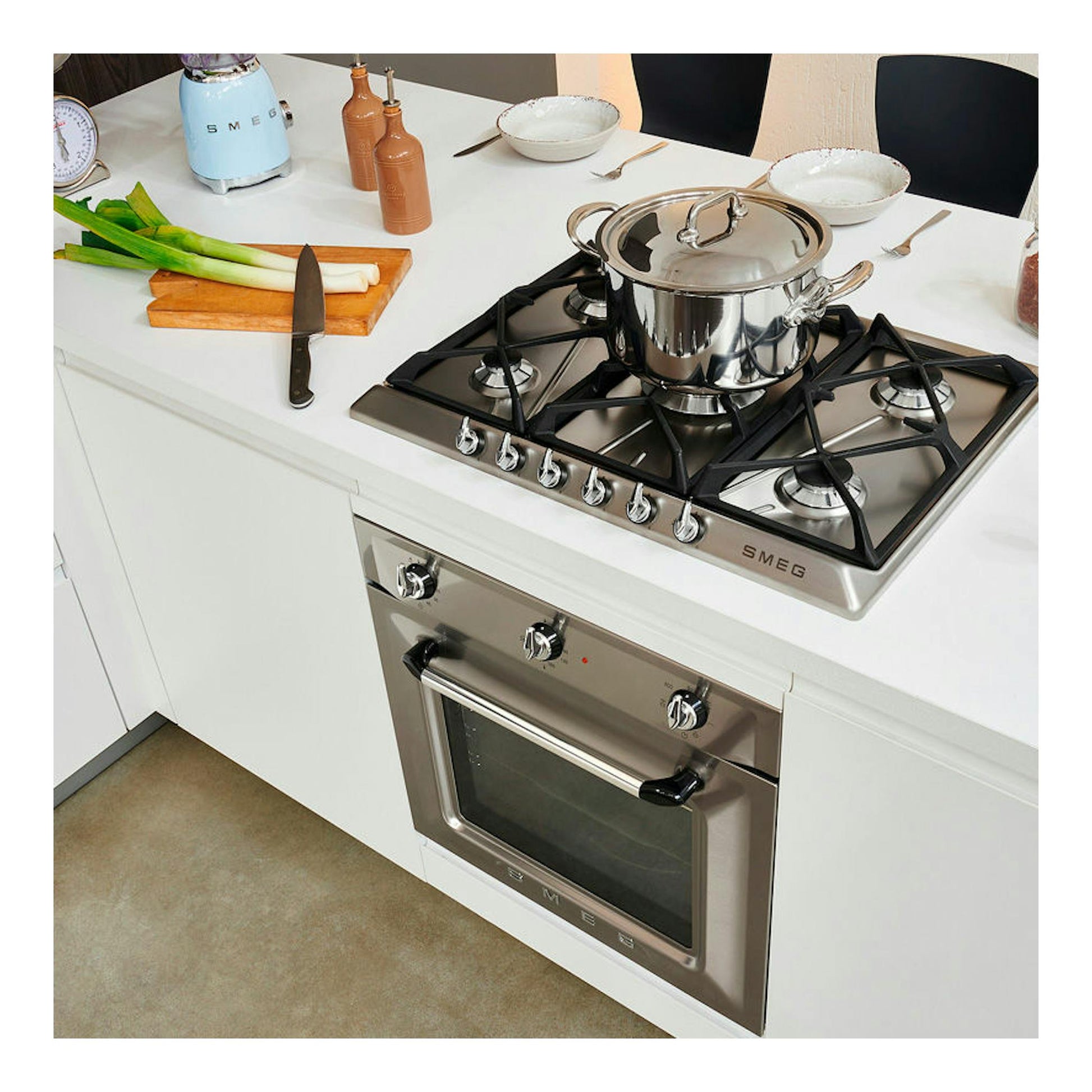 Horno Smeg SF6905X1 inox, vista frontal inclinada, integrado bajo encimera blanca, con placa de gas arriba.