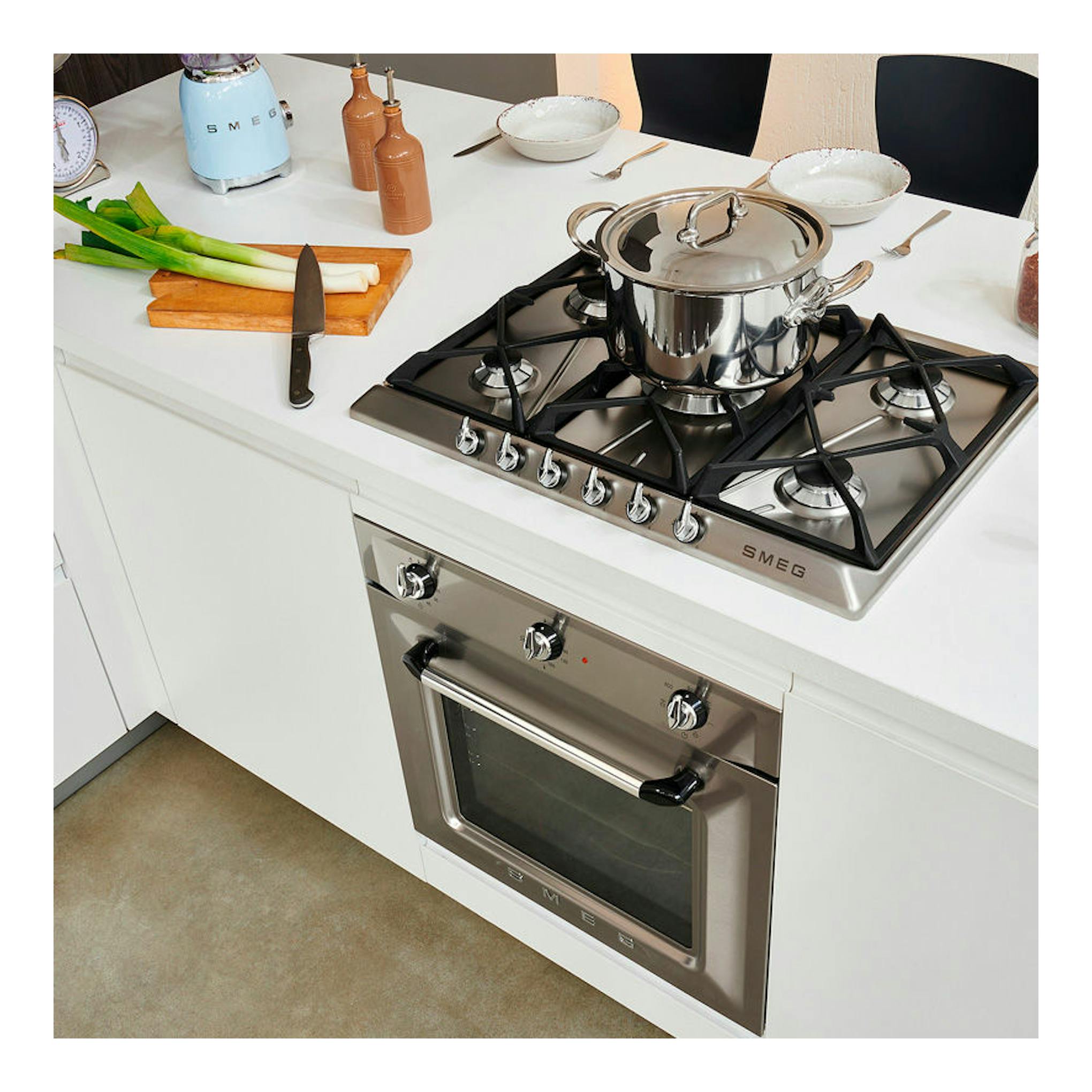 Horno Smeg SF6905X1 inox, vista frontal inclinada, integrado bajo encimera blanca, con placa de gas arriba.