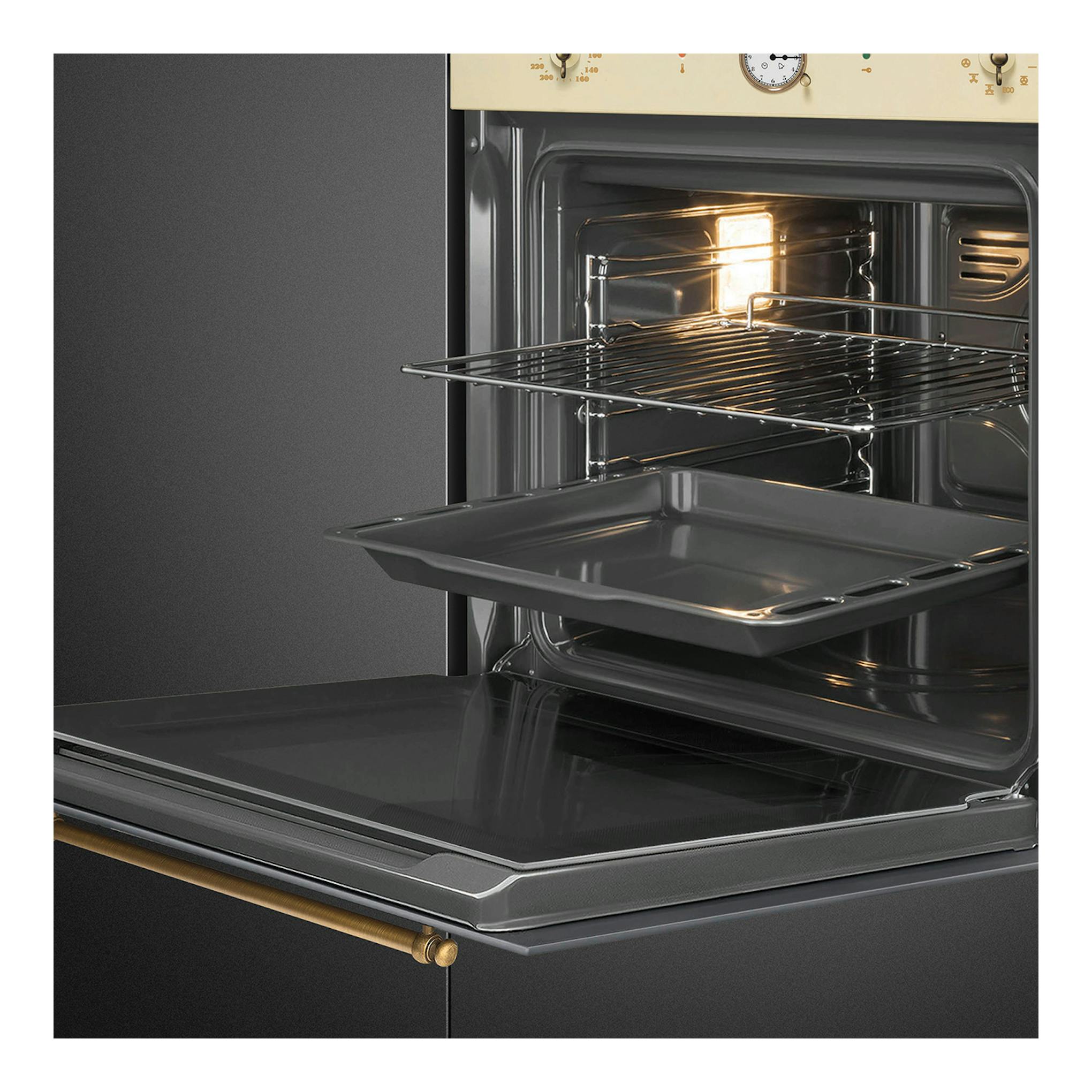 Horno multifunción Smeg SFP68C1TPO crema, puerta abatible abierta, interior negro con bandeja y rejilla.