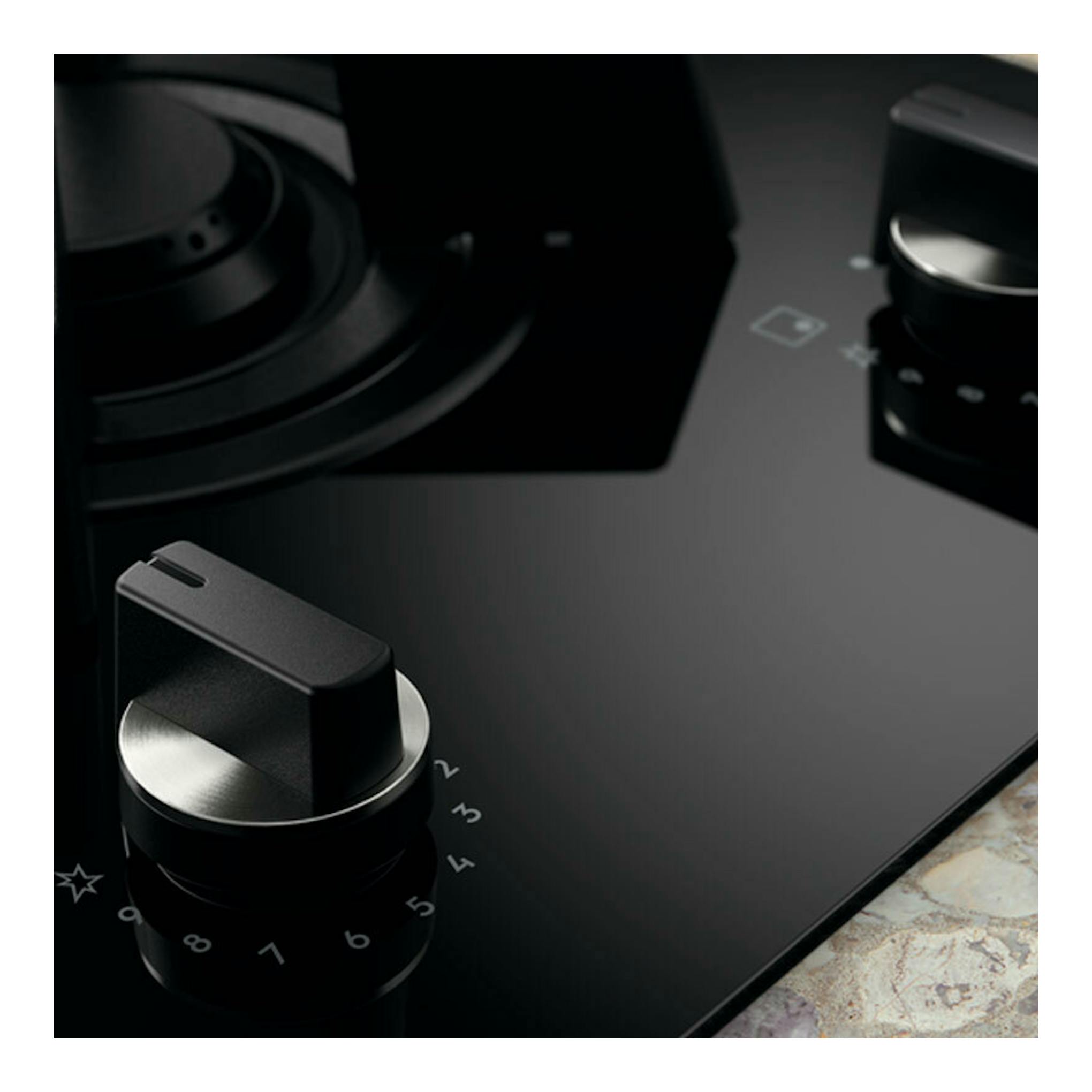 Placa de inducción Electrolux KDI641723K negra, vista en primer plano con mandos giratorios.