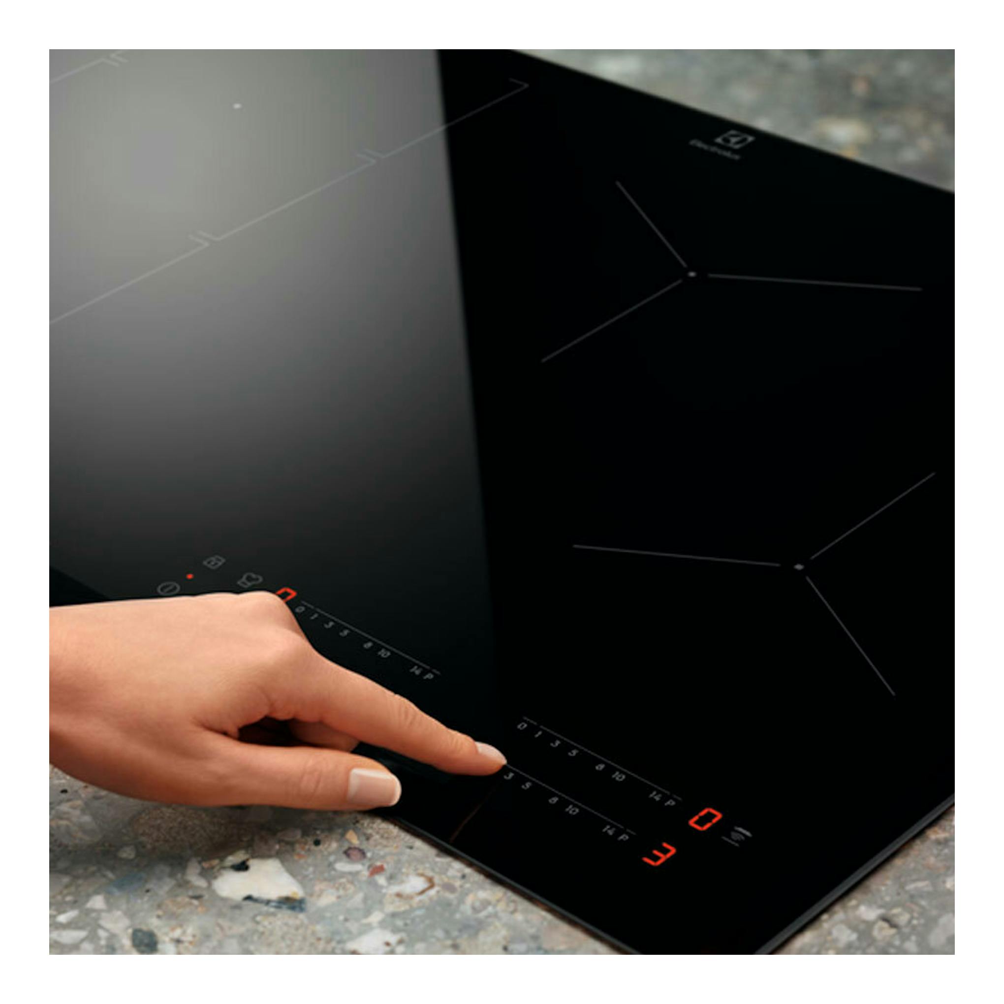 Placa de inducción Electrolux LIT6340CK negra, vista en ángulo, con mano ajustando controles táctiles.