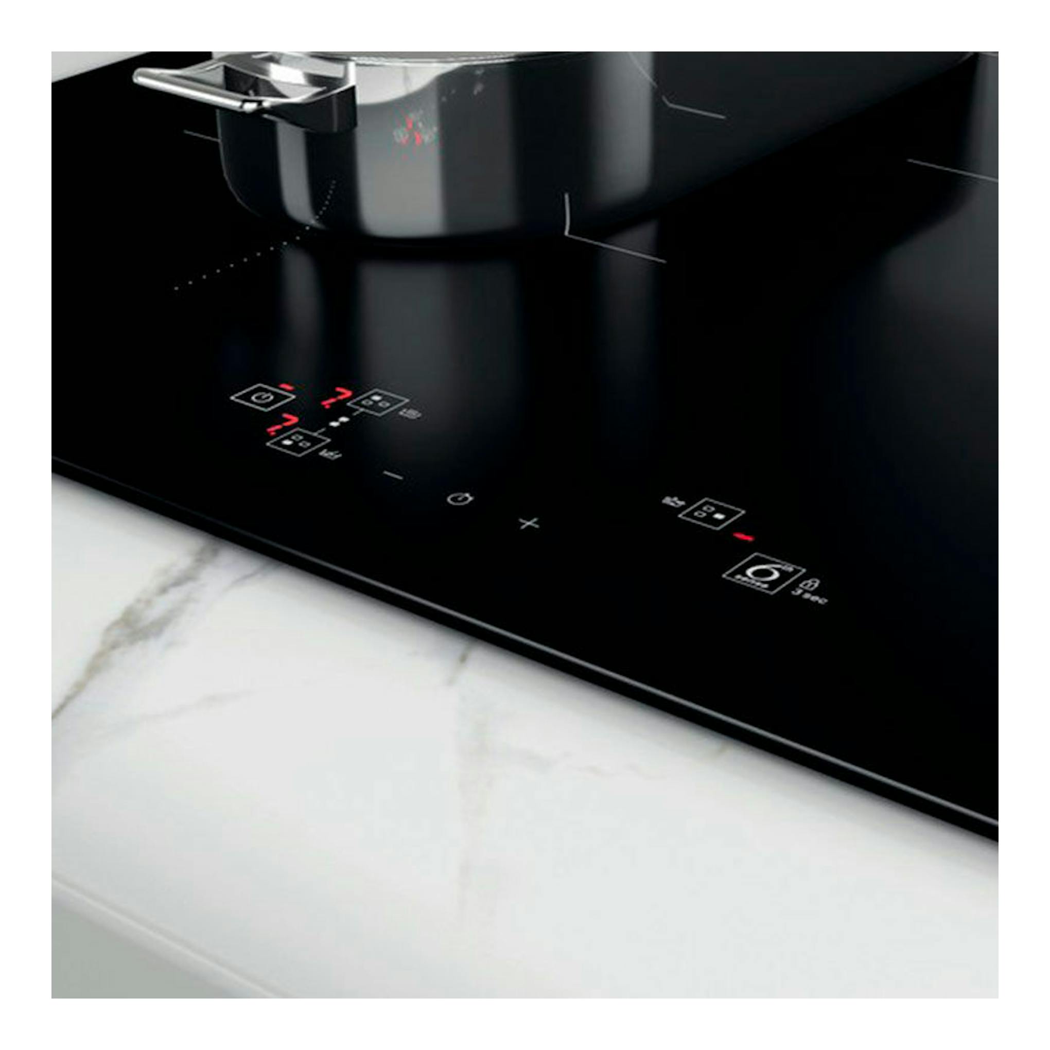 Parrilla de inducción Whirlpool WBQ4860NE, vista en ángulo, vidrio negro con controles táctiles y una olla.