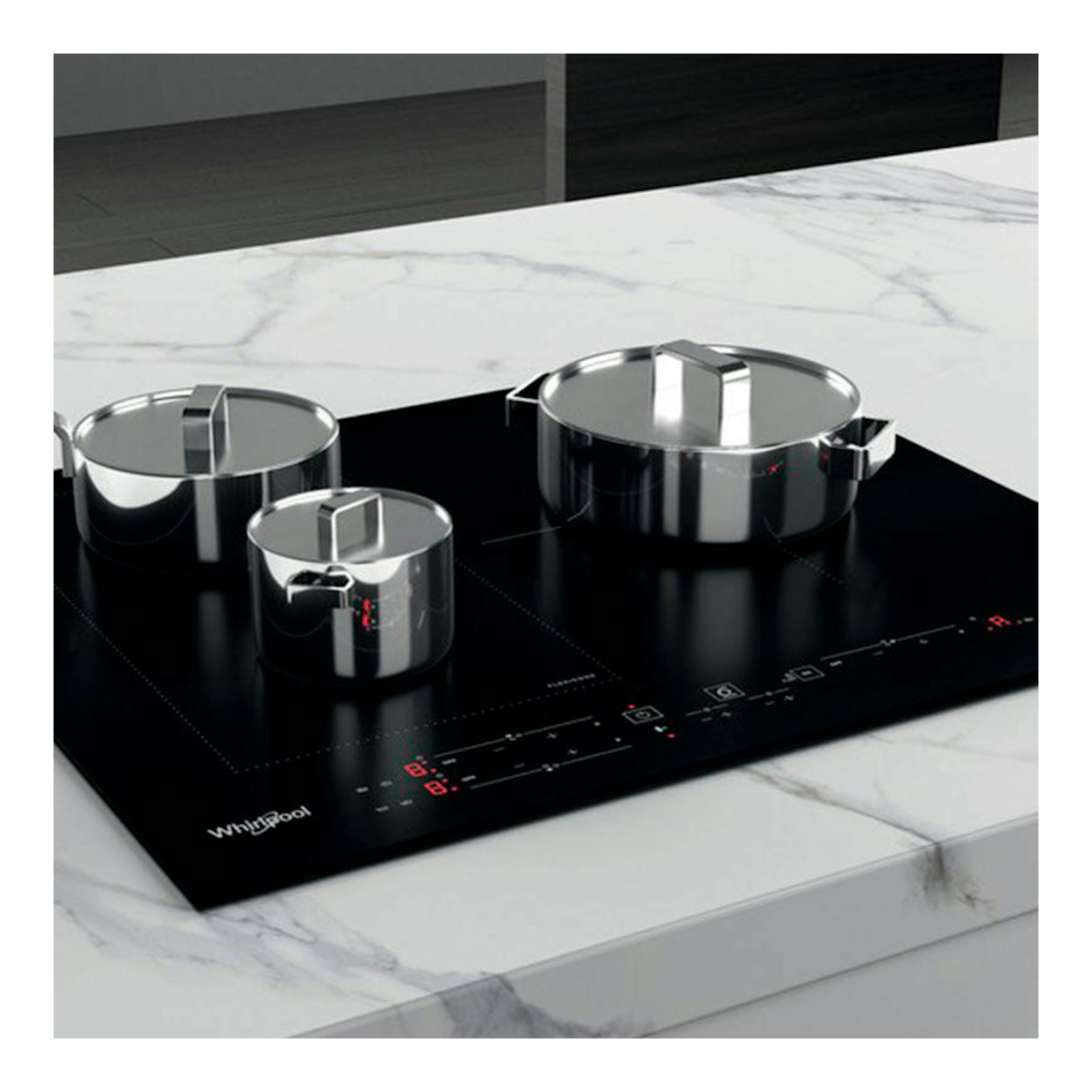 Parrilla de inducción Whirlpool WLB2760BF negra, vista en ángulo, con tres ollas de acero inoxidable.