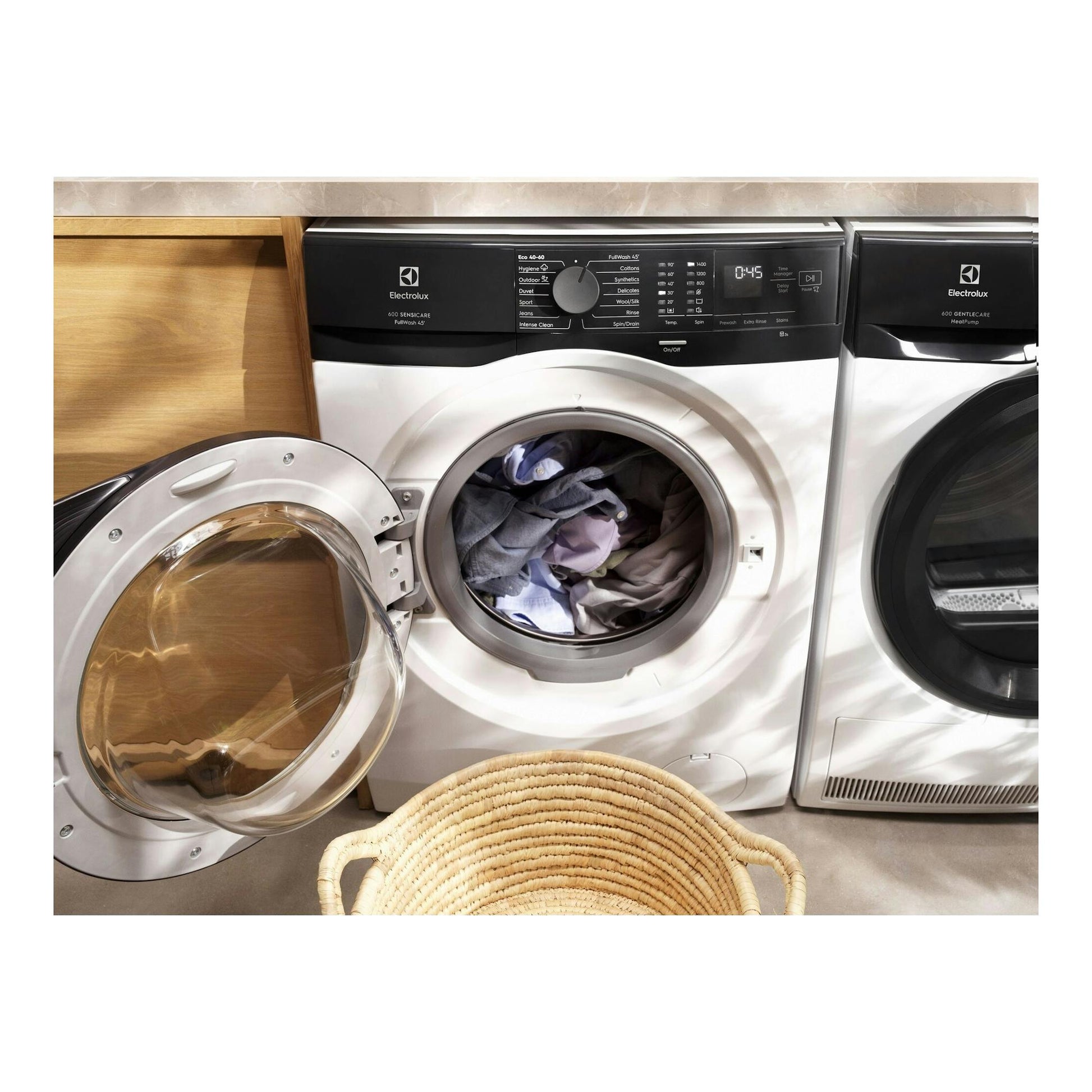 Lavadora frontal Electrolux blanca, con panel negro, puerta abierta y ropa dentro, vista frontal.