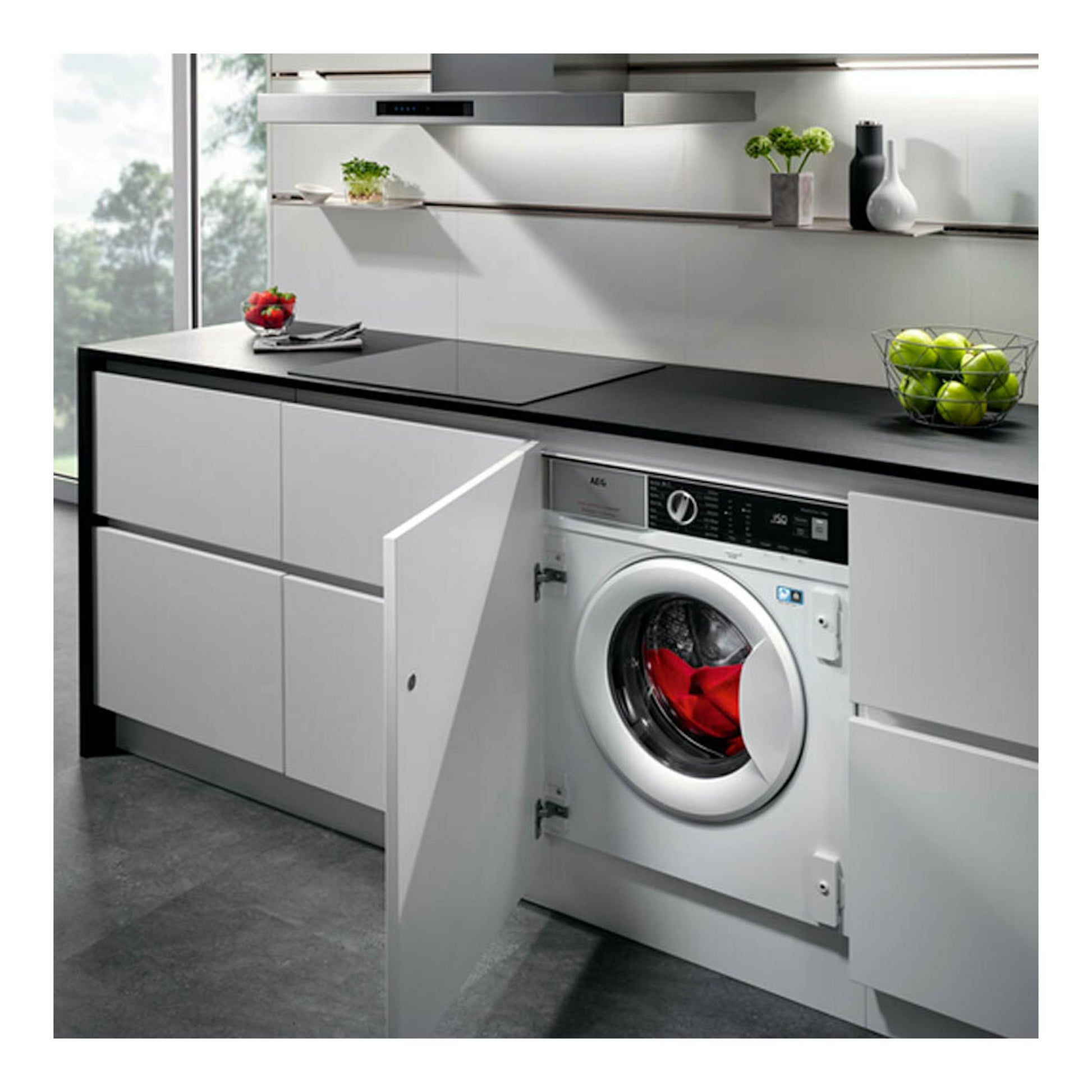 Lavadora integrable AEG LFN7G8434F blanca, vista frontal, instalada en mueble de cocina con la puerta abierta.