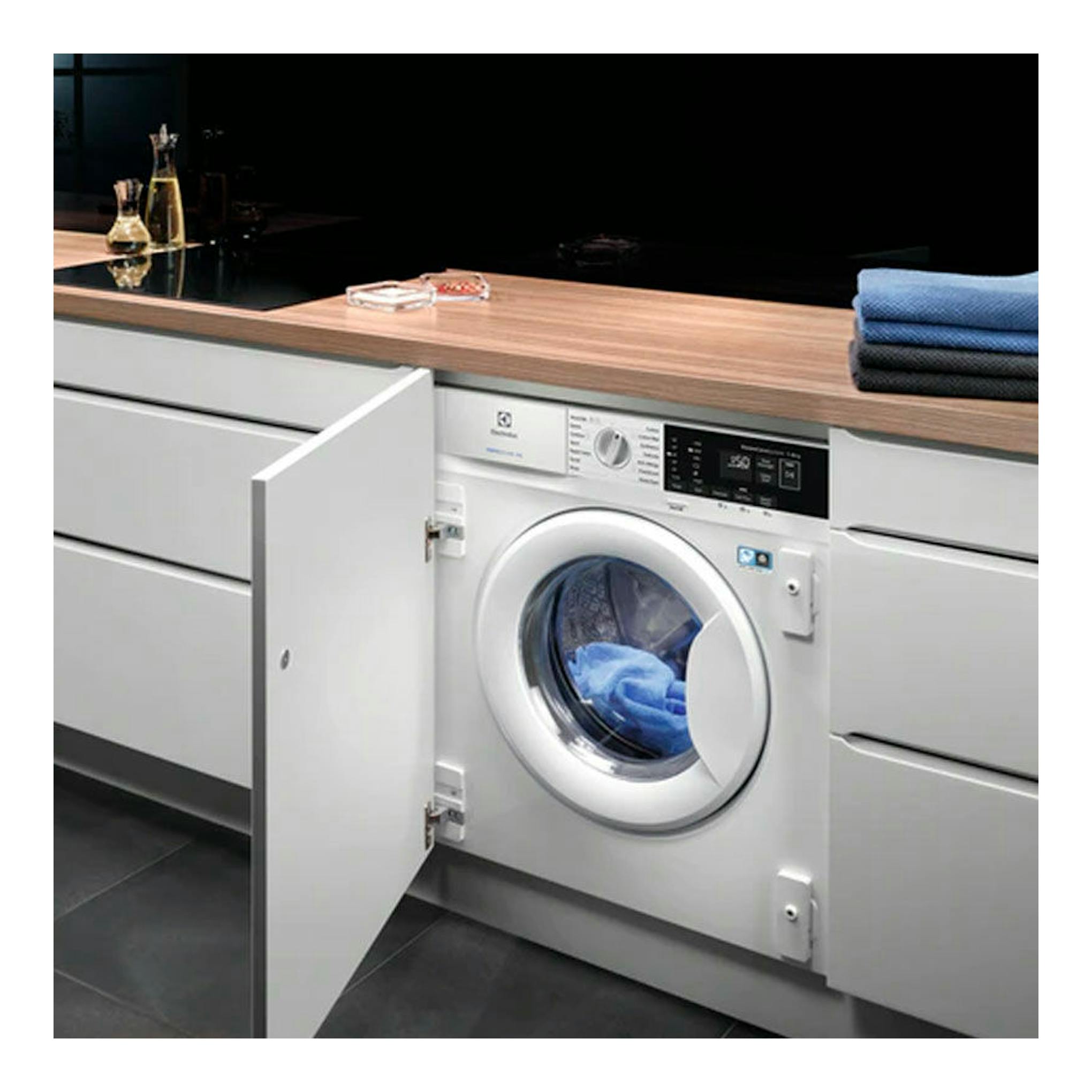 Lavadora integrable Electrolux blanca, vista frontal, con puerta abierta en mueble de cocina.