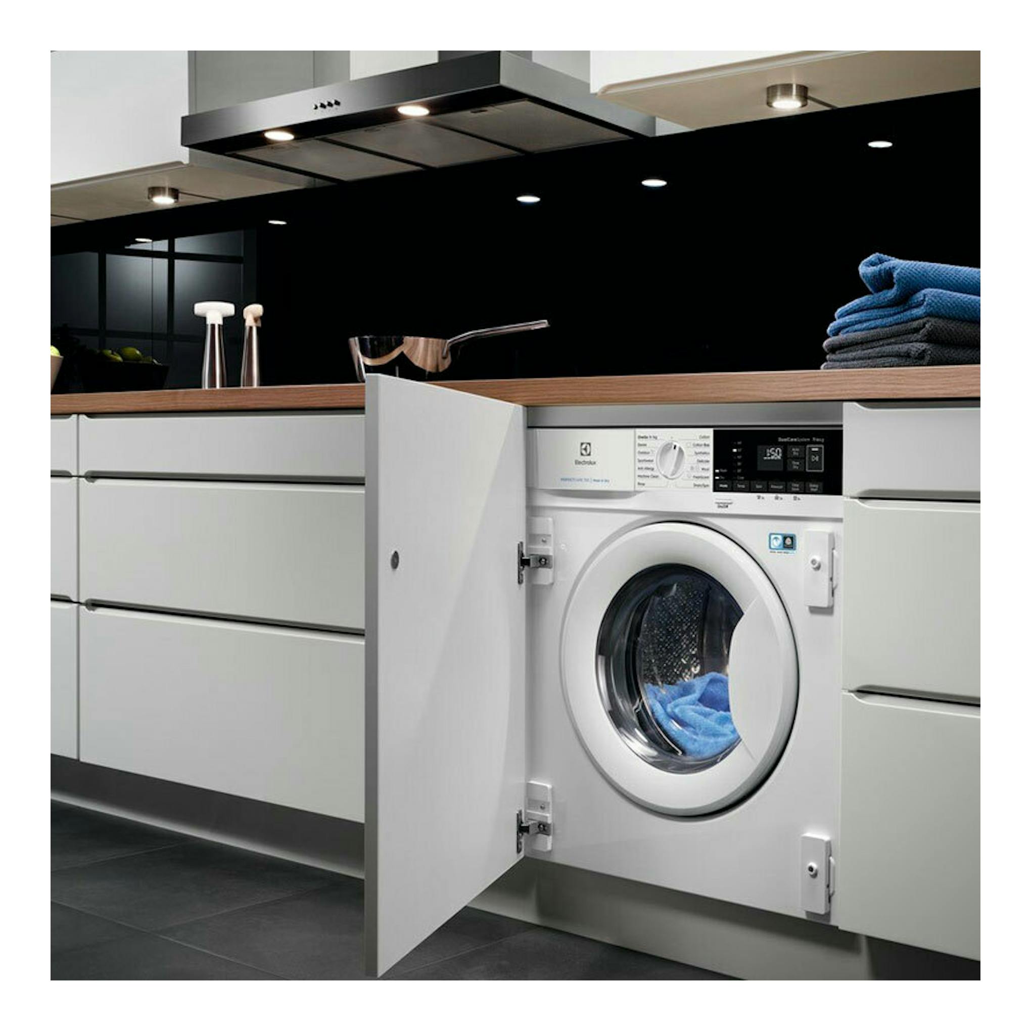 Lavasecadora integrable Electrolux EN7W4862OF blanca, vista frontal, con puerta abierta bajo encimera en cocina.