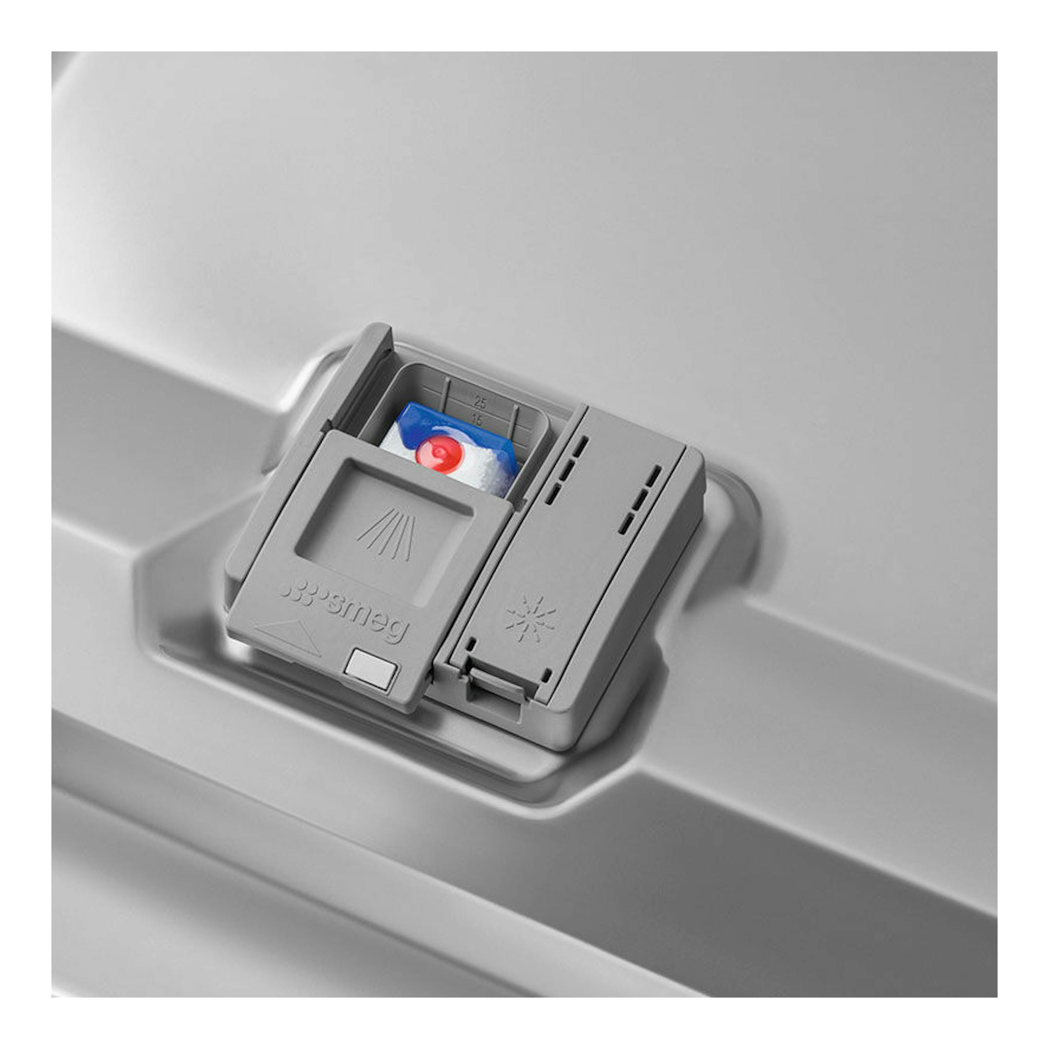 Primer plano del dispensador de detergente de un lavavajillas Smeg, en plástico gris.
