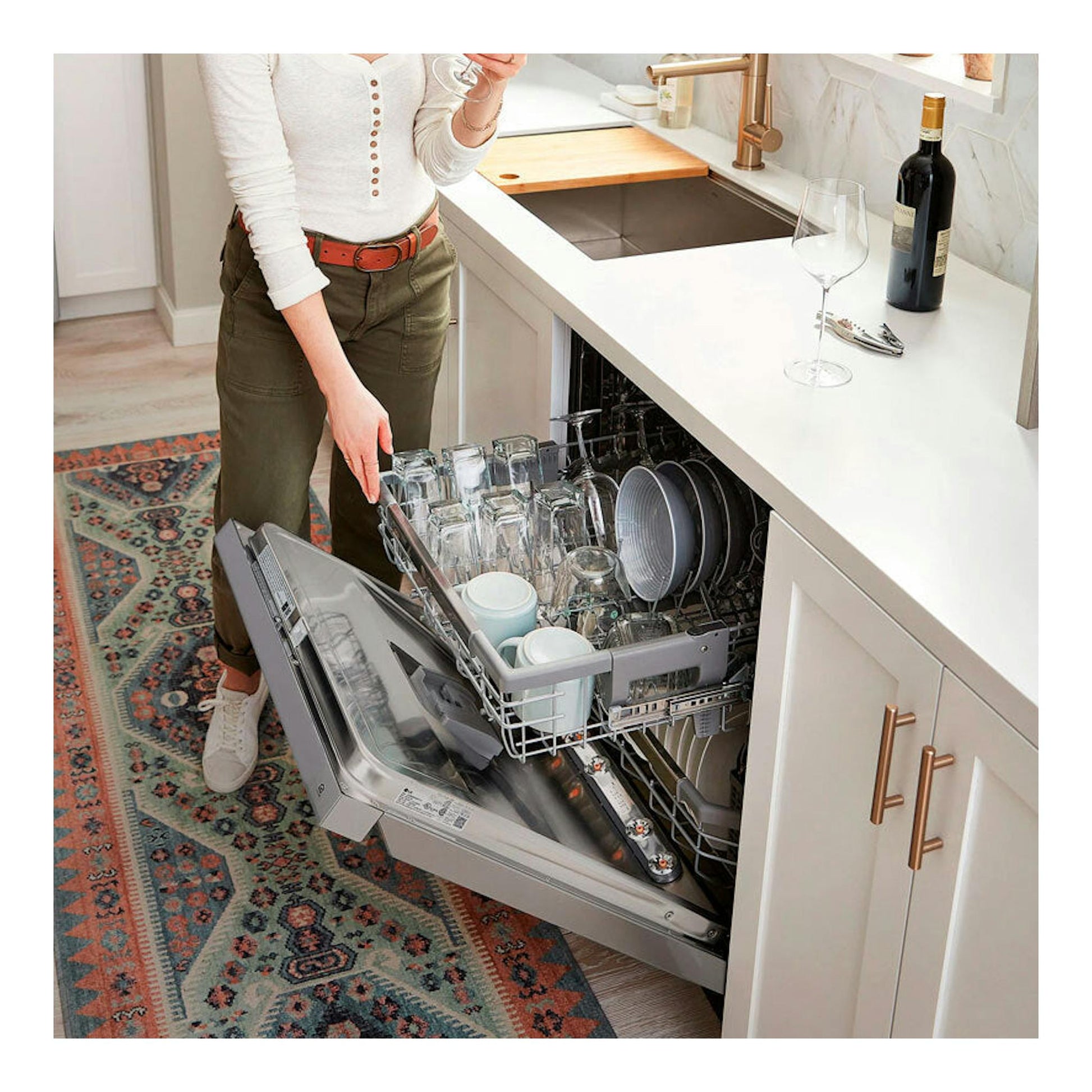 Lavavajillas LG DF242FP de 60 cm, empotrado y abierto en cocina, con cestas llenas de vasos y platos.