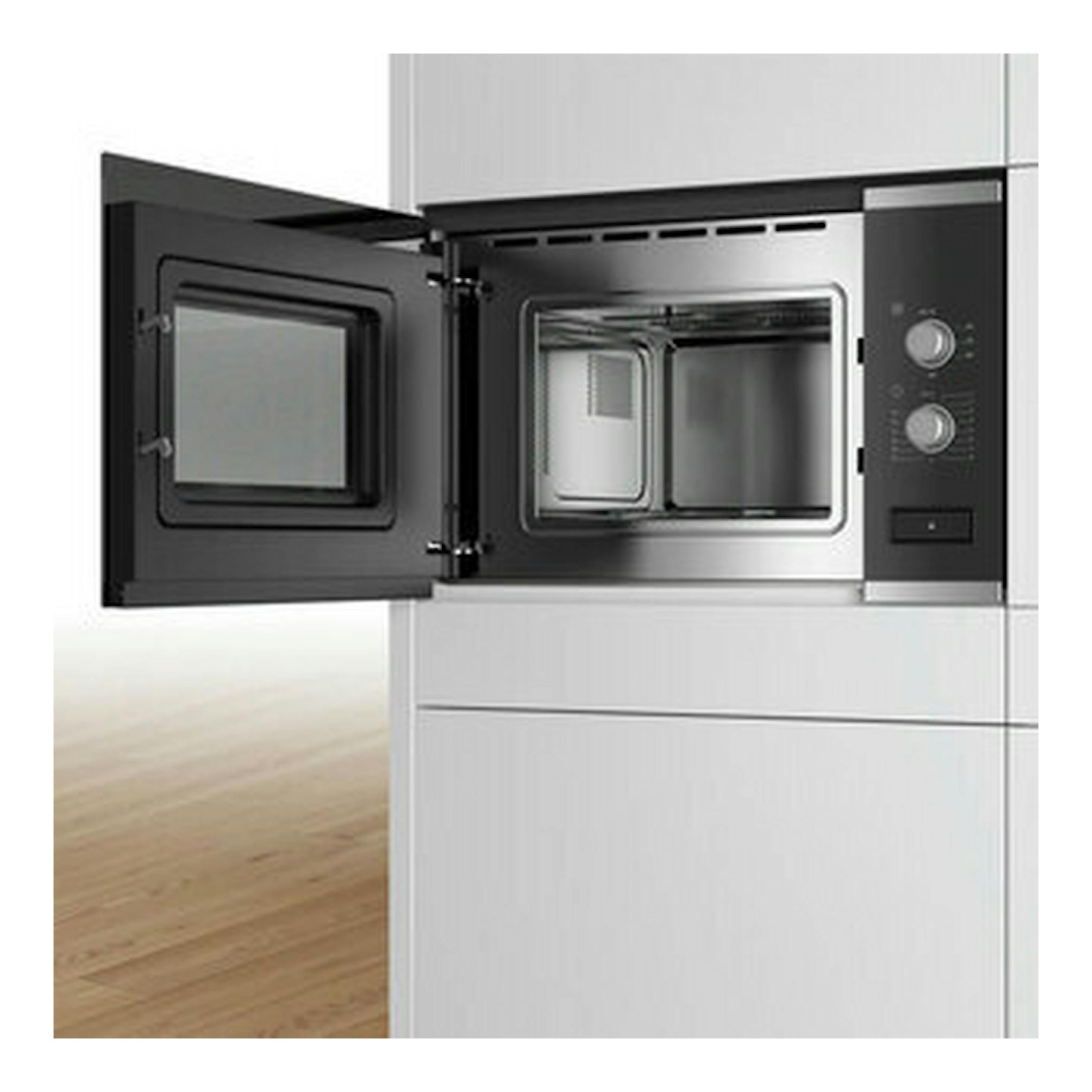 Microondas empotrable Bosch BFL520MS0 negro, vista frontal con la puerta abierta en un mueble blanco.