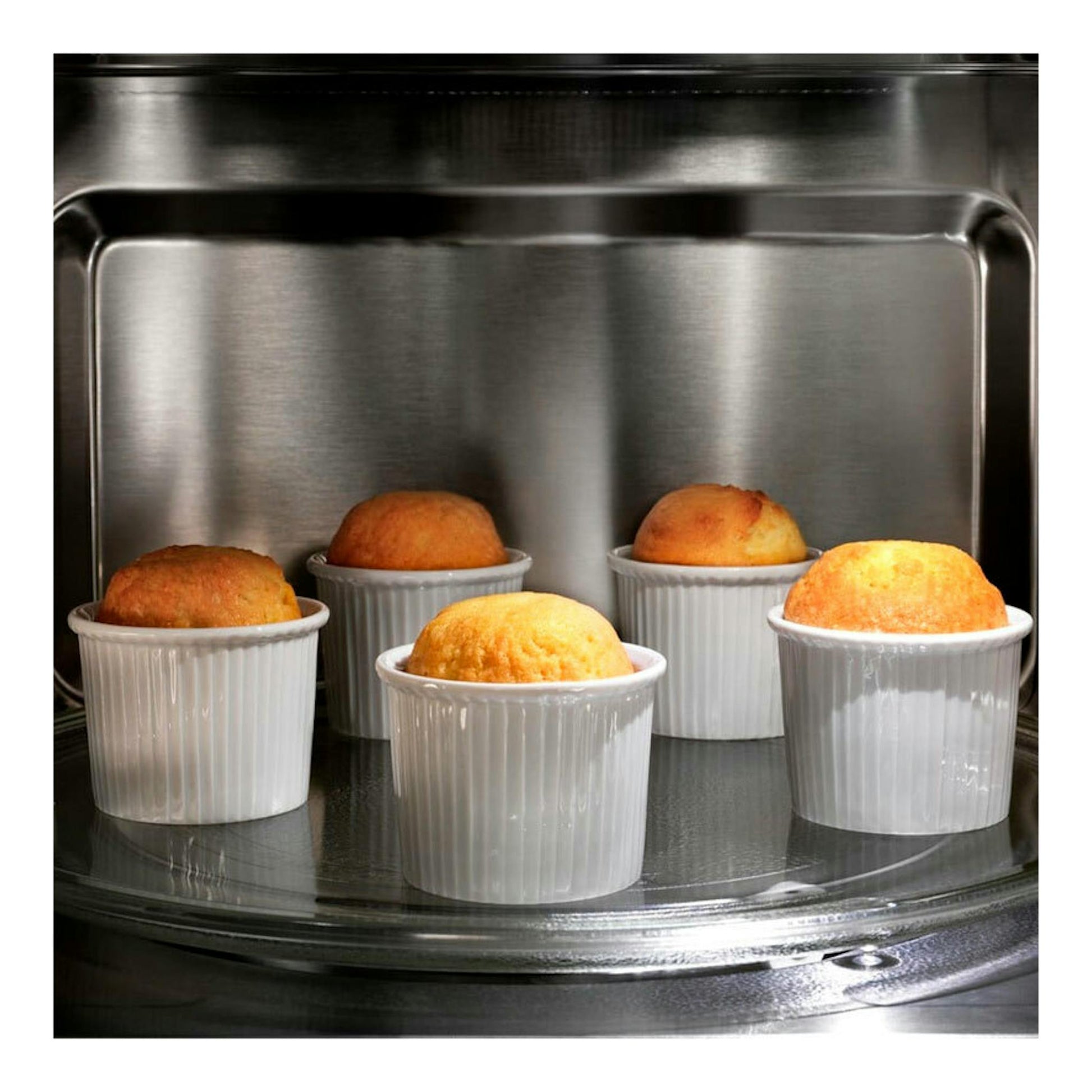 Microondas Electrolux KMSD203MMX inox, vista interior con cinco moldes blancos y magdalenas en el plato.