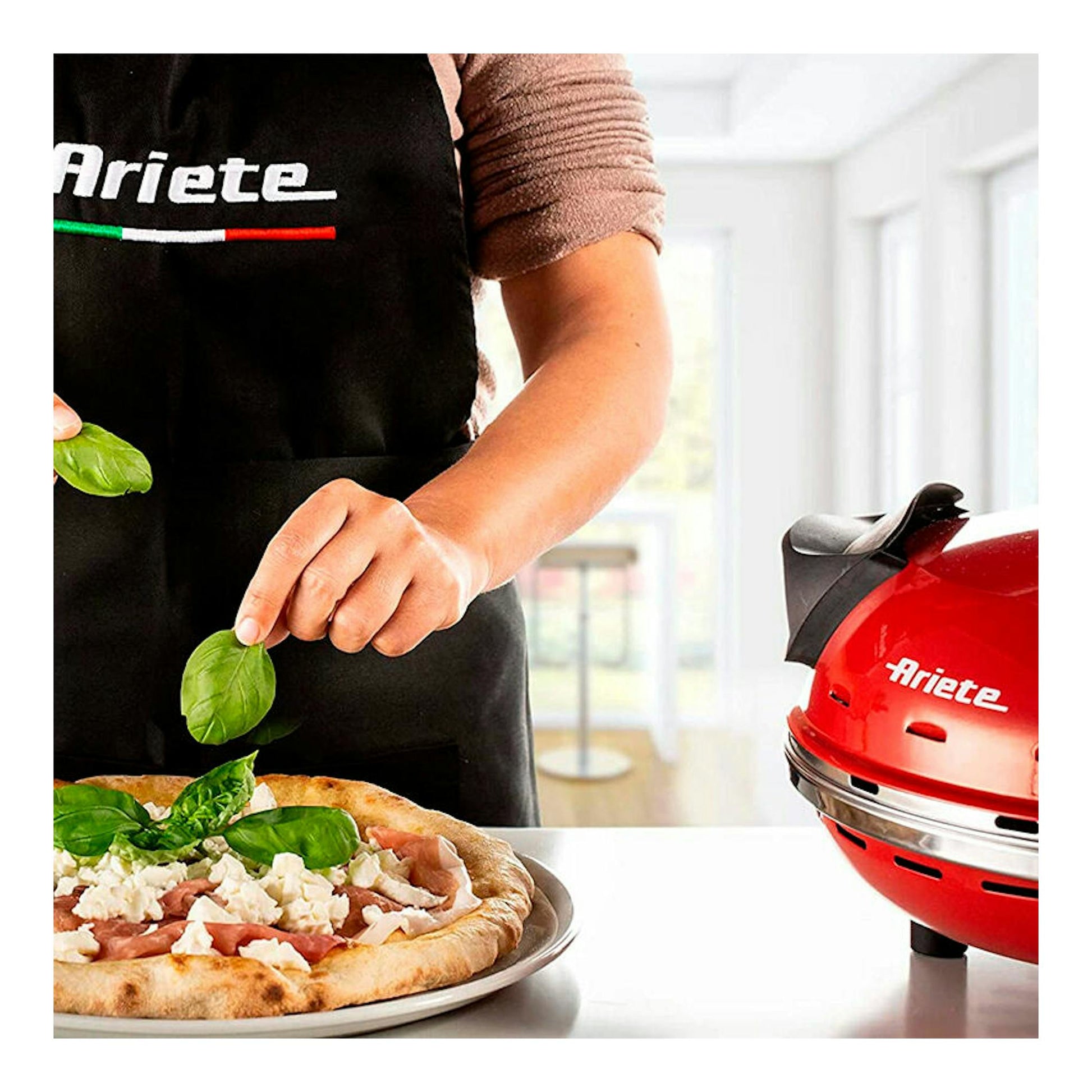 Horno para pizza Ariete 909 rojo, vista frontal, junto a una pizza en primer plano.