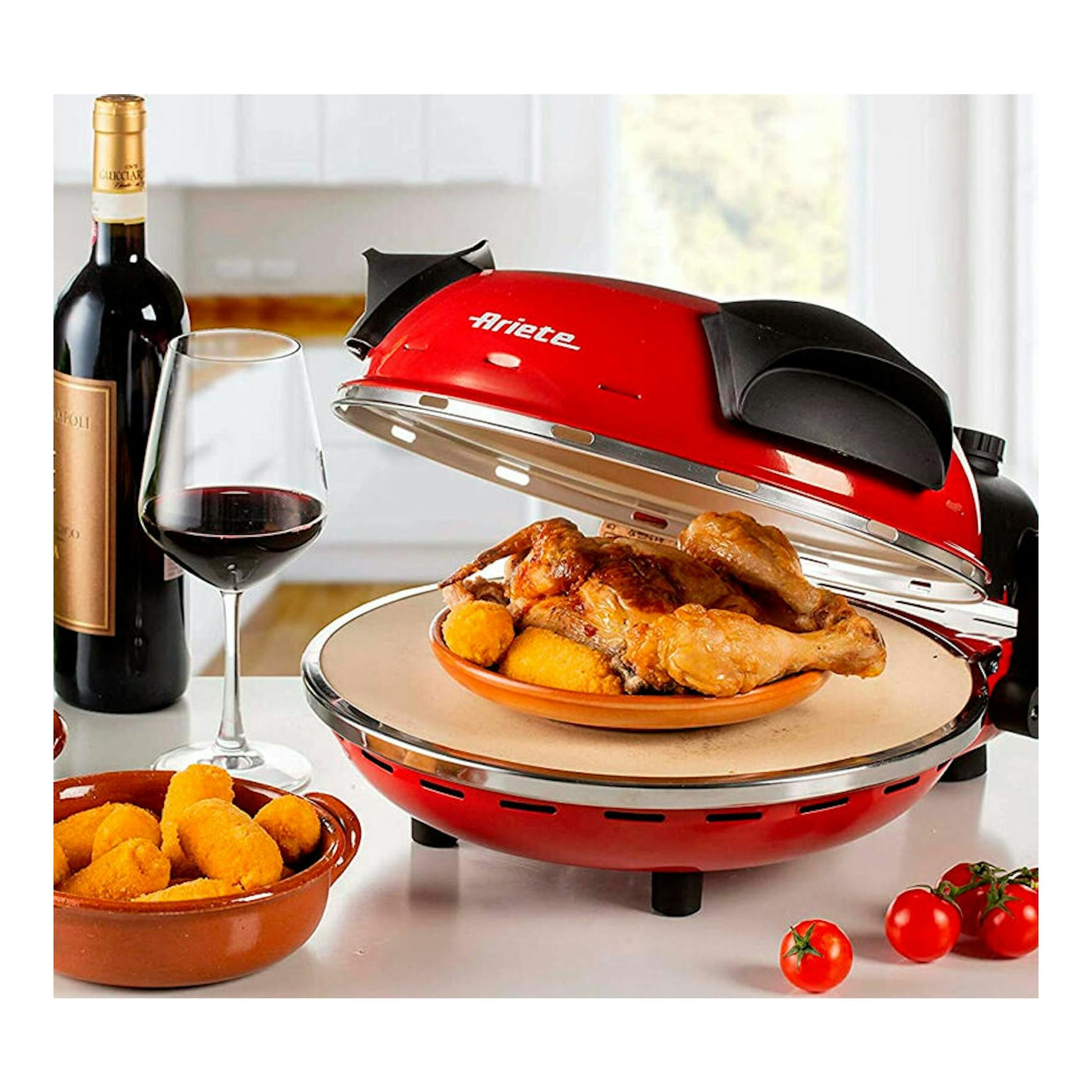 Mini horno para pizza Ariete 909 rojo, abierto, con pollo y guarnición sobre la mesa.