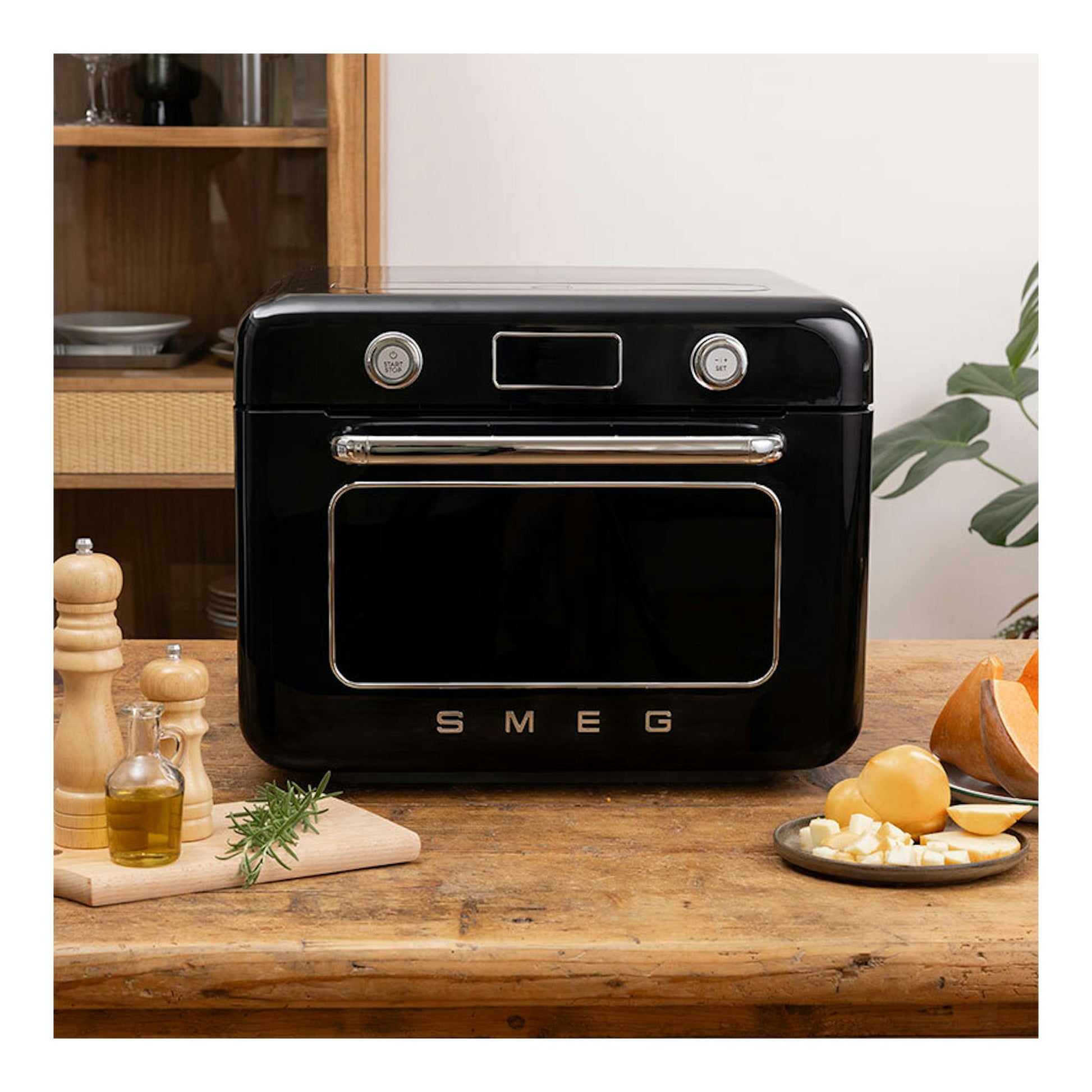 Minihorno Smeg COF01BLEU negro, vista frontal, sobre una mesa de madera.
