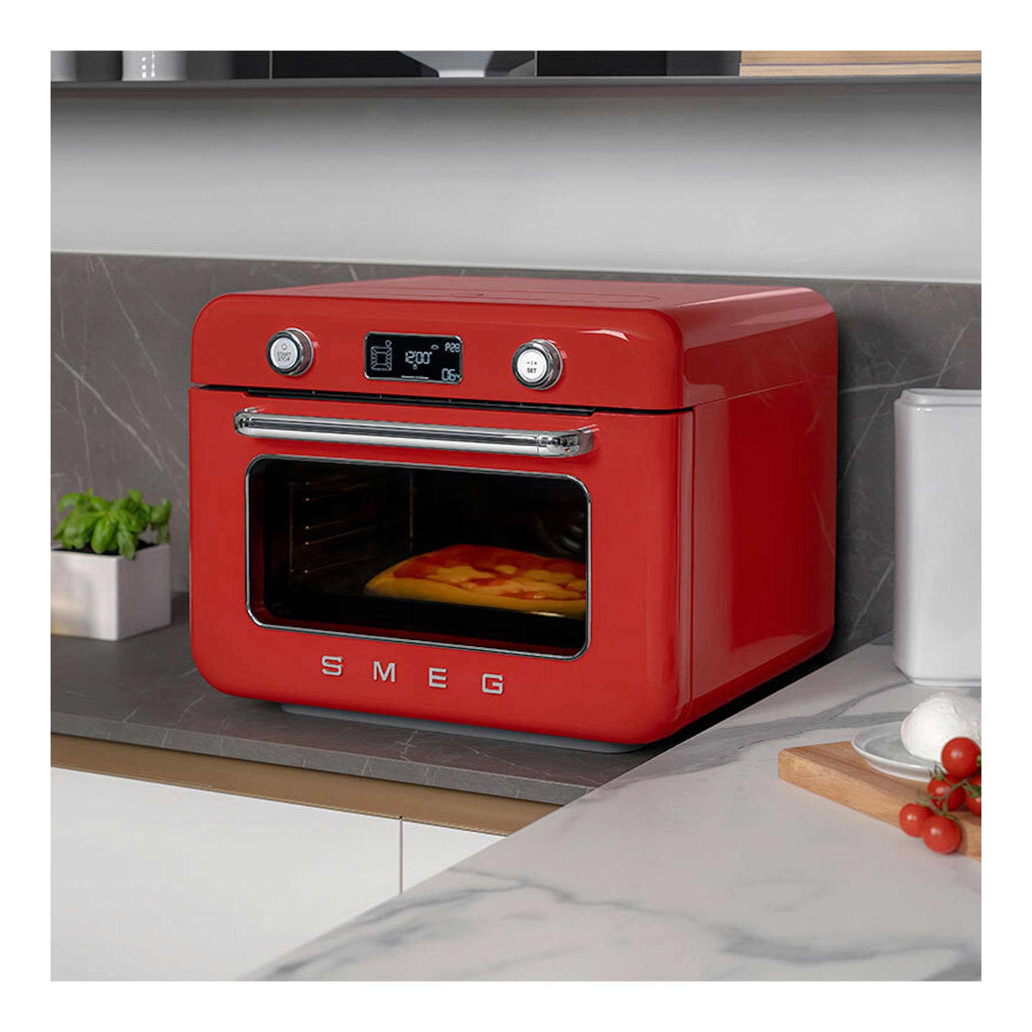 Minihorno Smeg COF01RDEU rojo, vista frontal en ángulo, sobre encimera, con pantalla digital y puerta de cristal.