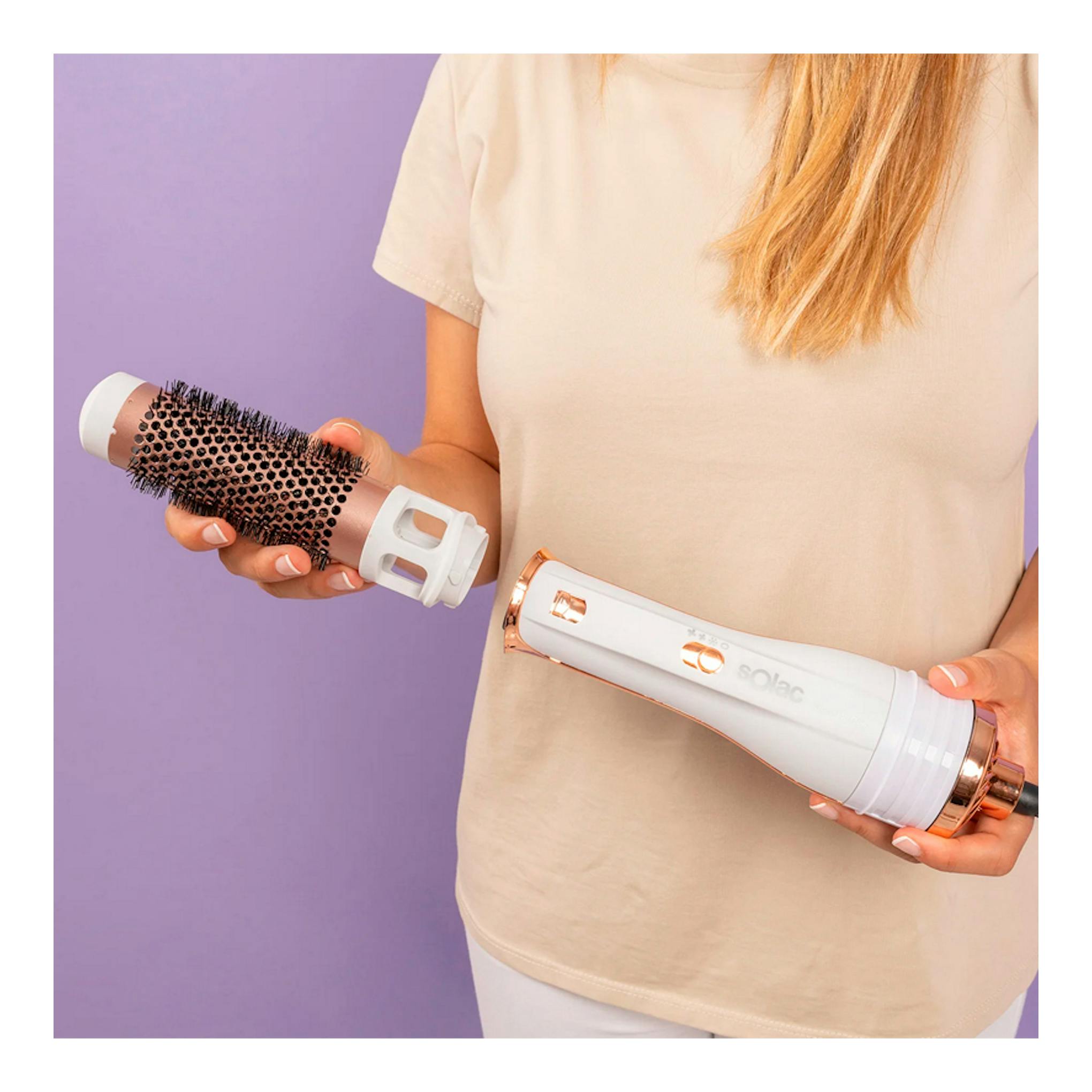 Moldeador Solac MD7405 Expert Ion Flow blanco y rosa, con accesorio cepillo, sostenido por una mujer.