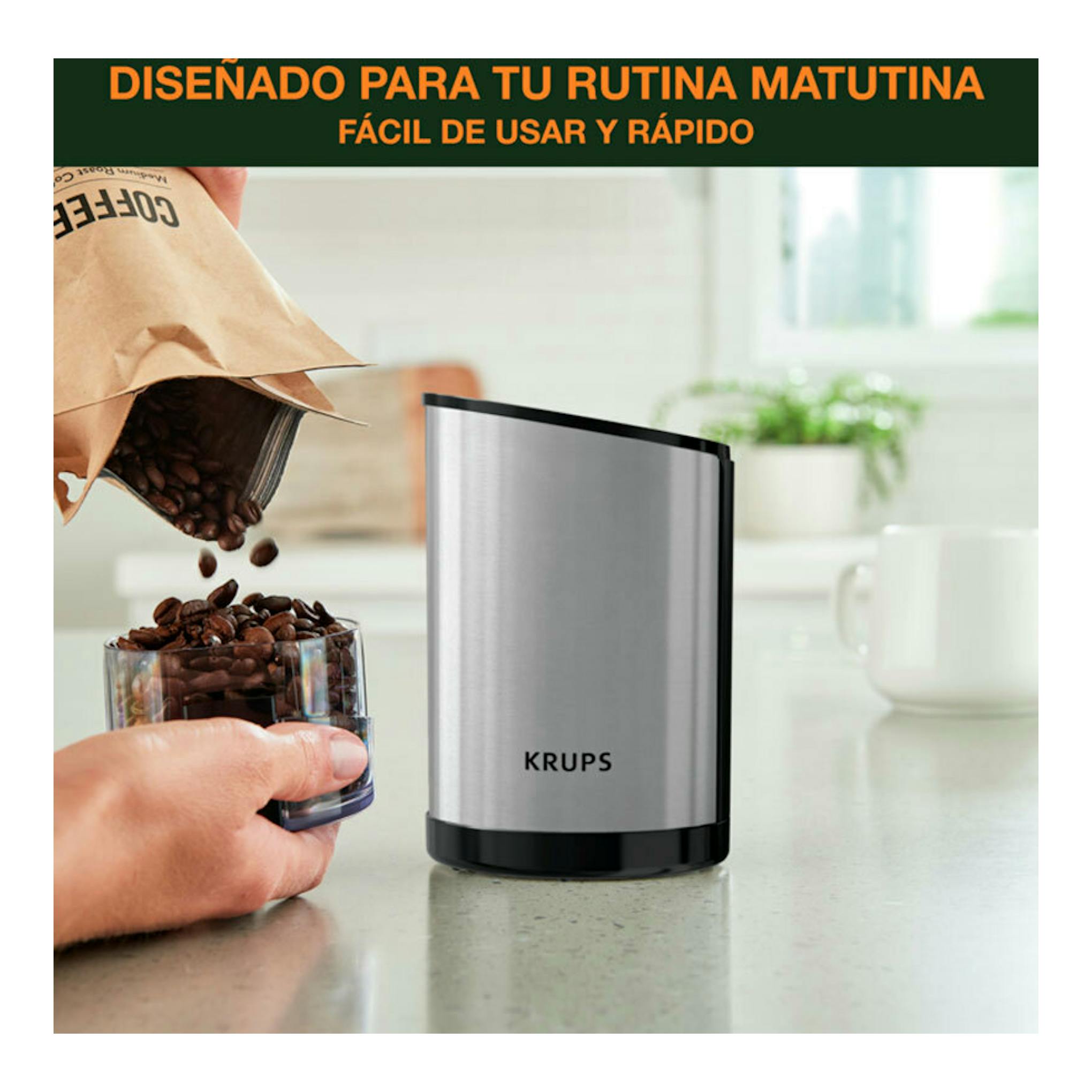 Molinillo de café Krups GX204D10 plateado y negro, vista frontal, sobre encimera junto a granos de café.