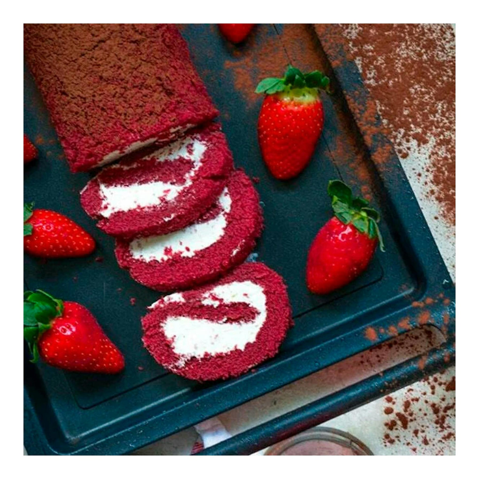 Parrilla plana negra rectangular con bizcocho rojo y fresas, vista cenital.