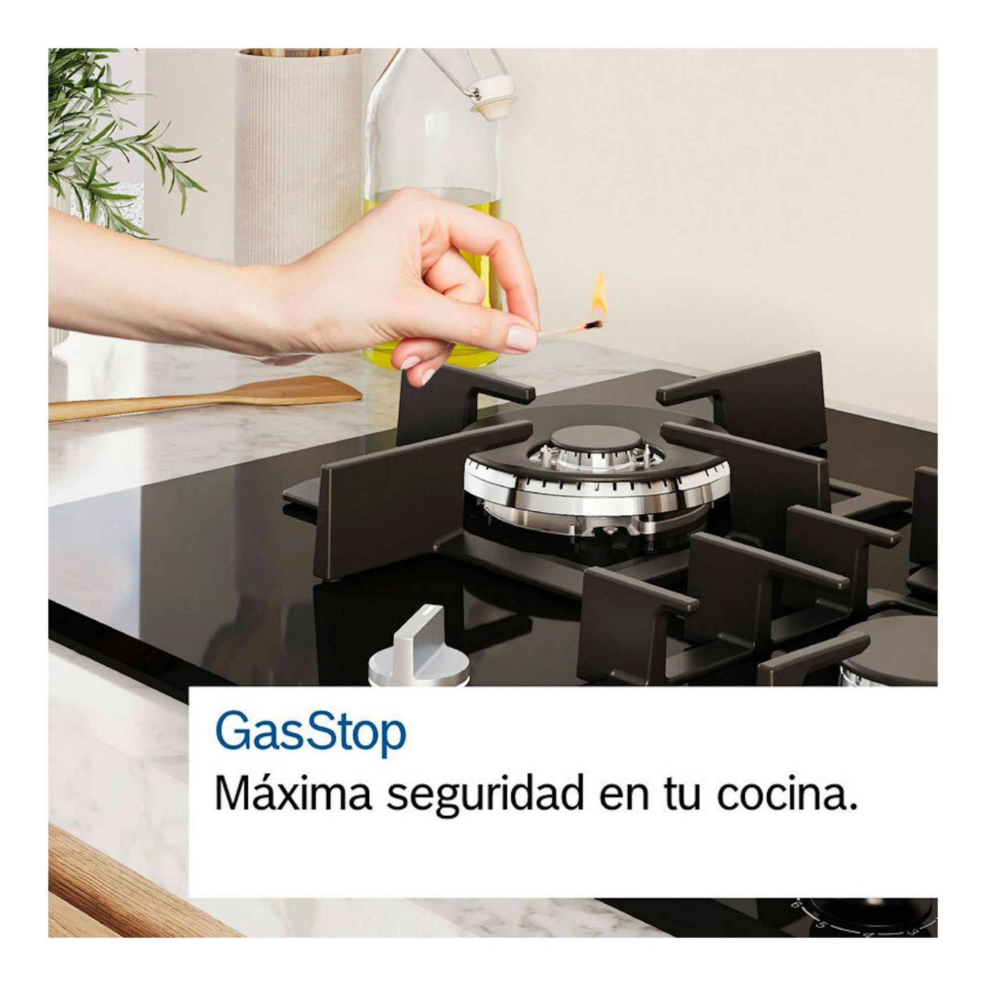 Placa de gas Bosch PCR9A5I90 de 90 cm, negra, vista frontal, con una mano encendiendo un quemador con un fósforo.