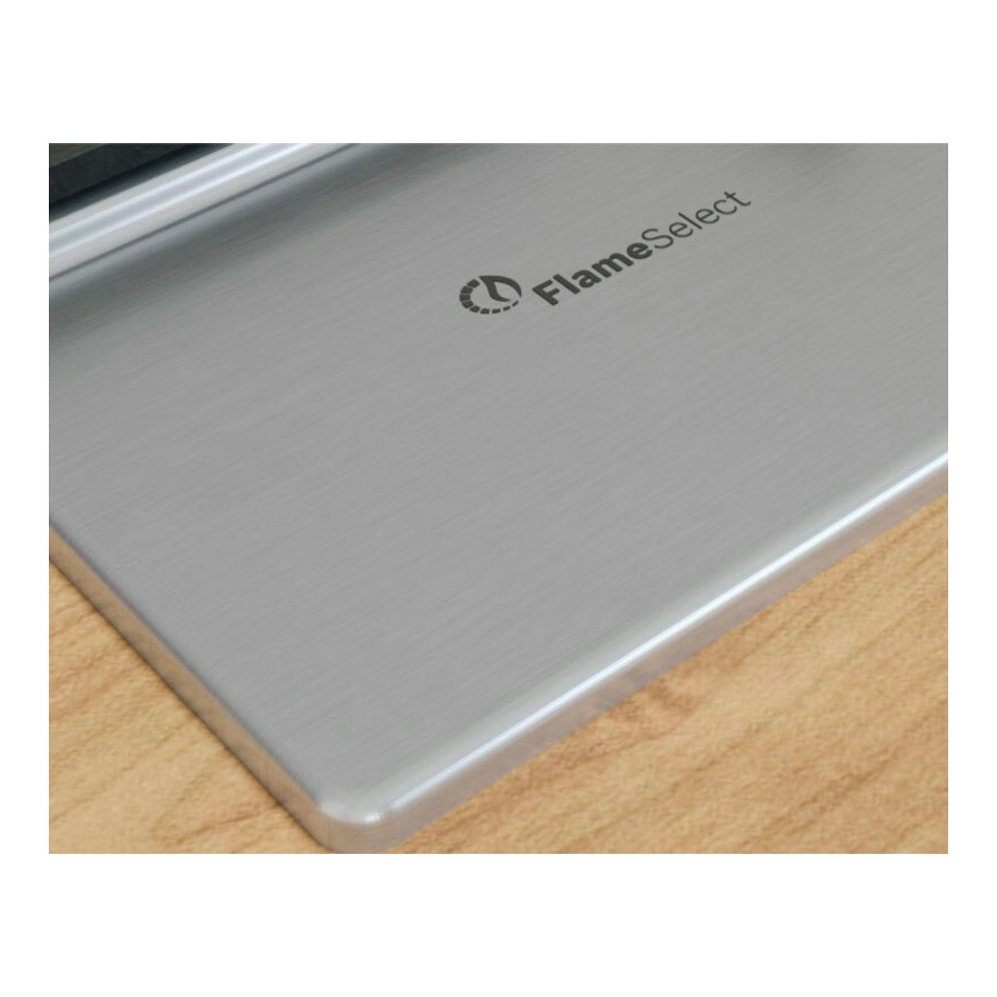 Detalle de una placa de acero inoxidable con logo FlamaSelect, vista en ángulo de una esquina.