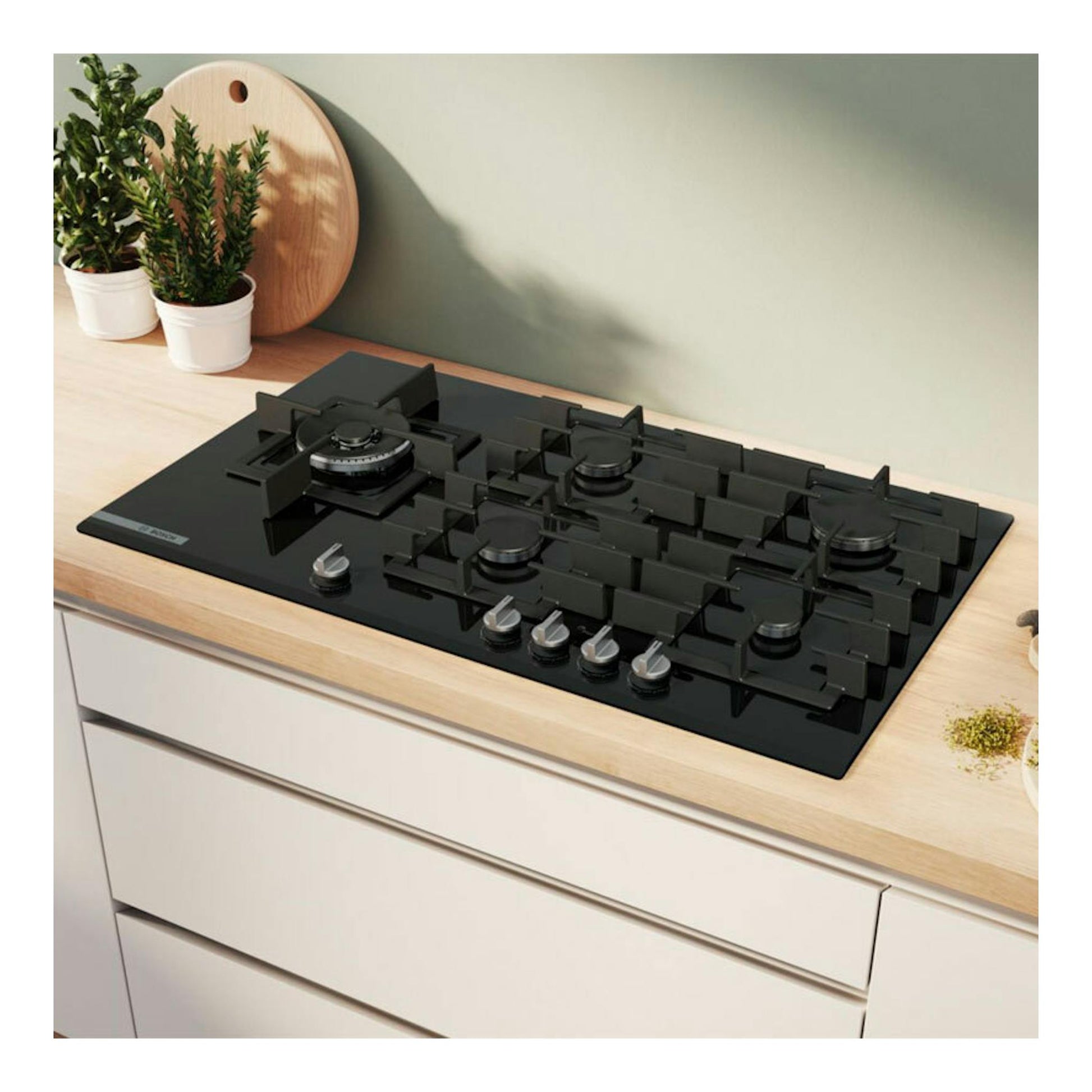 Placa de gas Bosch PRS9A6H40 negra, vista en ángulo sobre encimera de madera, con cinco fuegos.