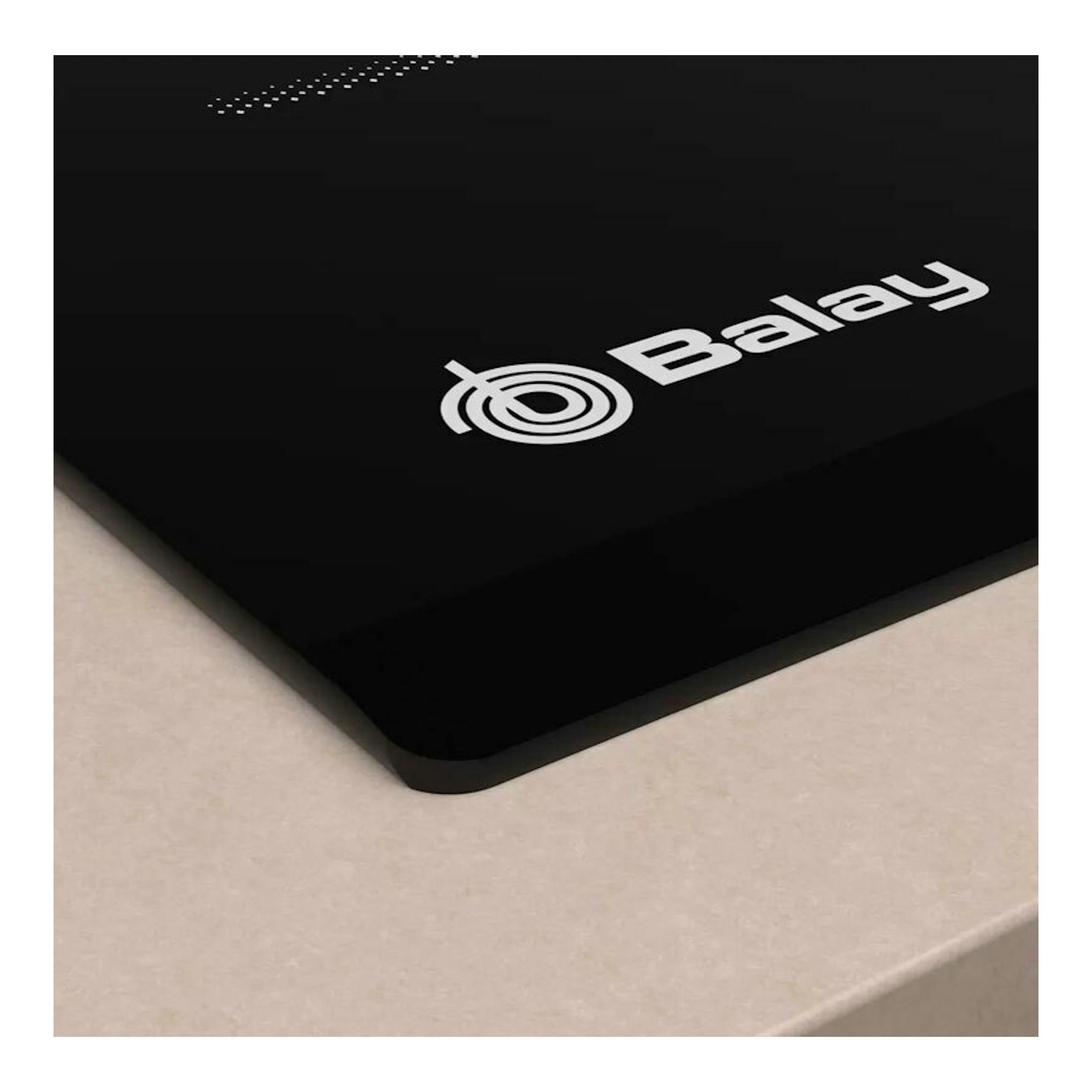 Placa de inducción Balay 3EB864FR negra, vista en ángulo sobre encimera beige.
