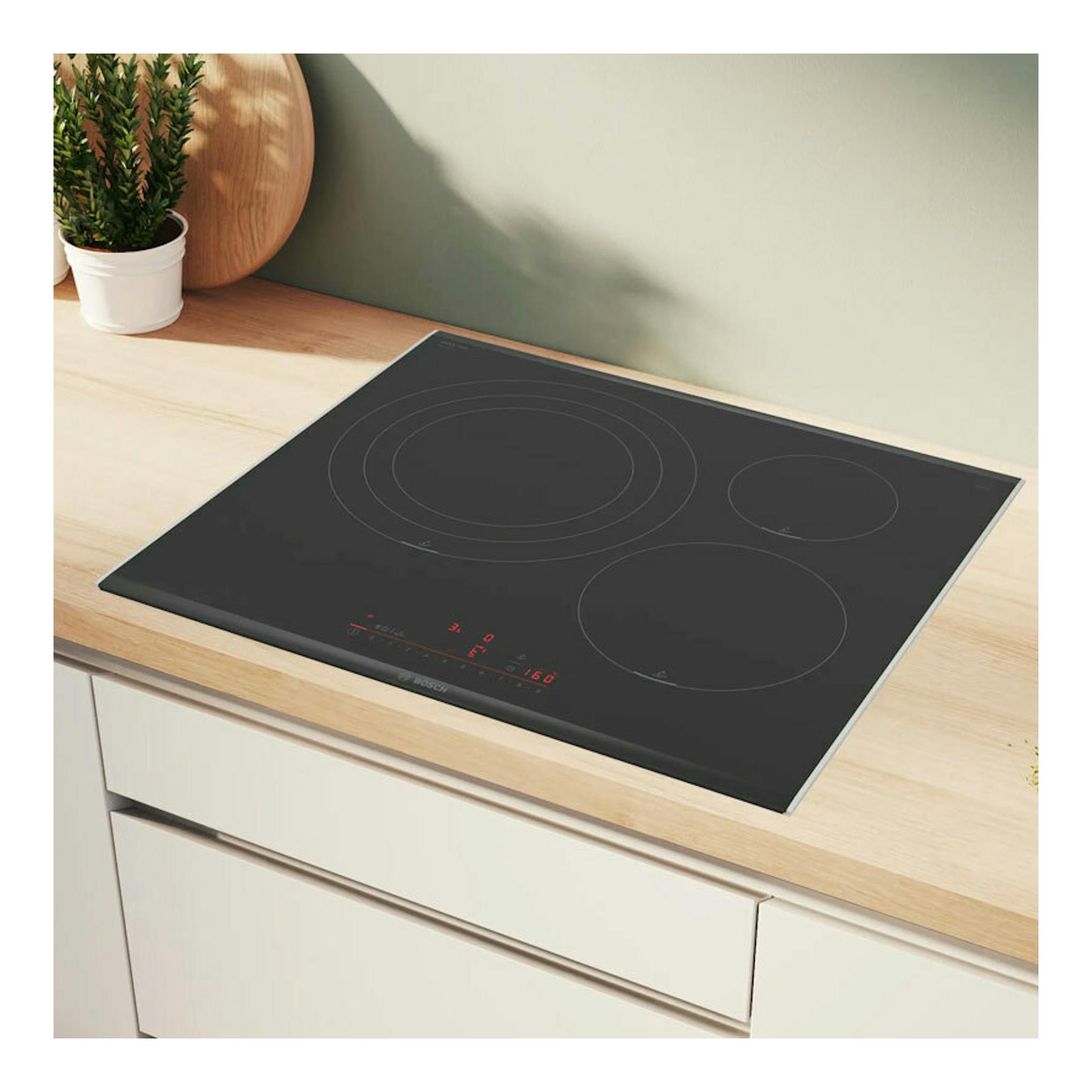 Placa de inducción Bosch PID675HC1E negra, vista en ángulo sobre encimera de madera.