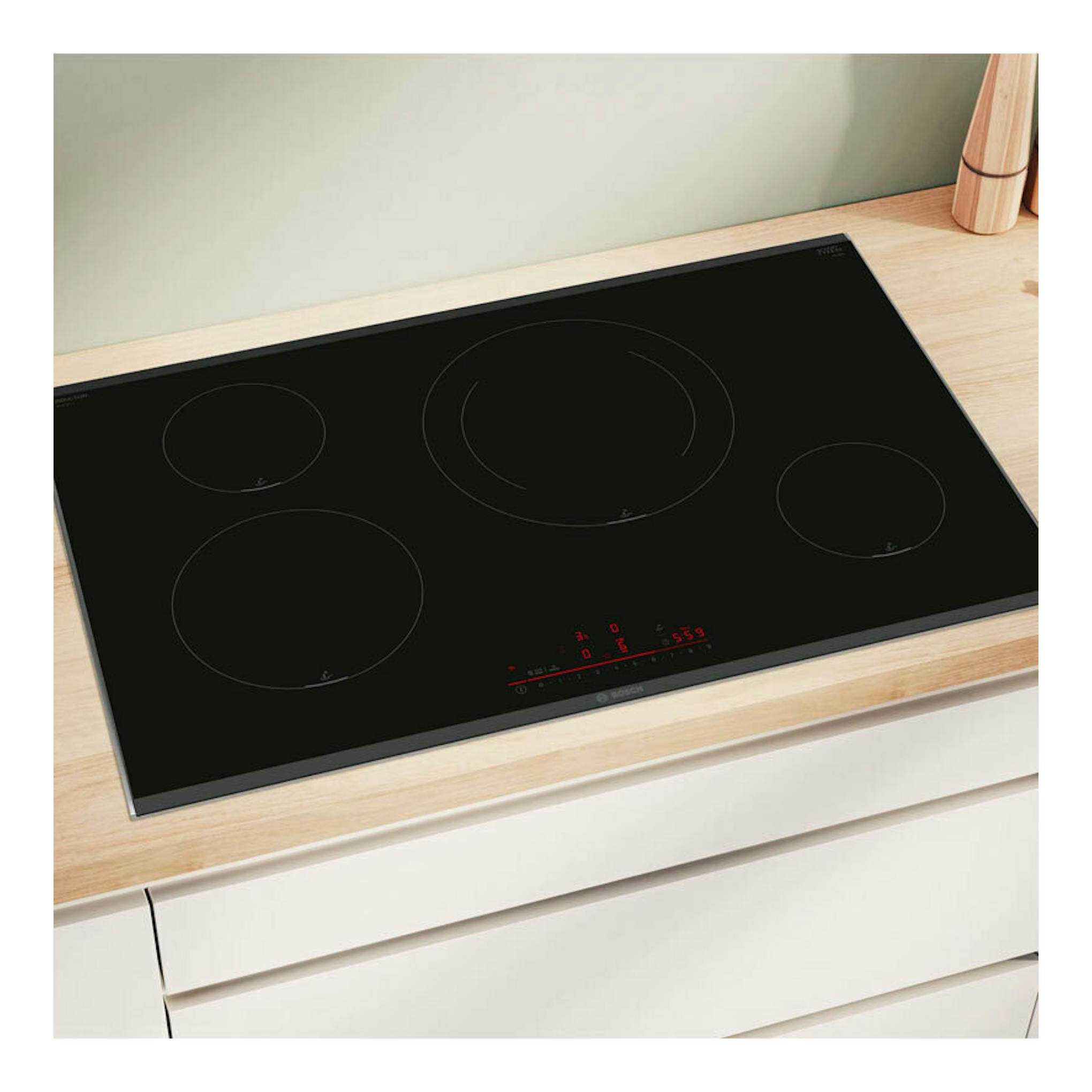 Placa de inducción Bosch PIE875HC1E negra, vista cenital inclinada, empotrada sobre encimera de madera.