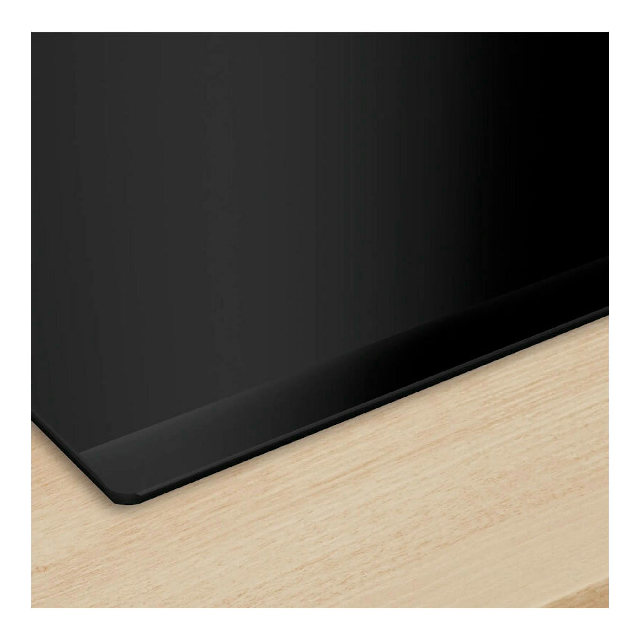 Placa de inducción Bosch PVQ631HC1E negra, vista en ángulo sobre encimera de madera clara.