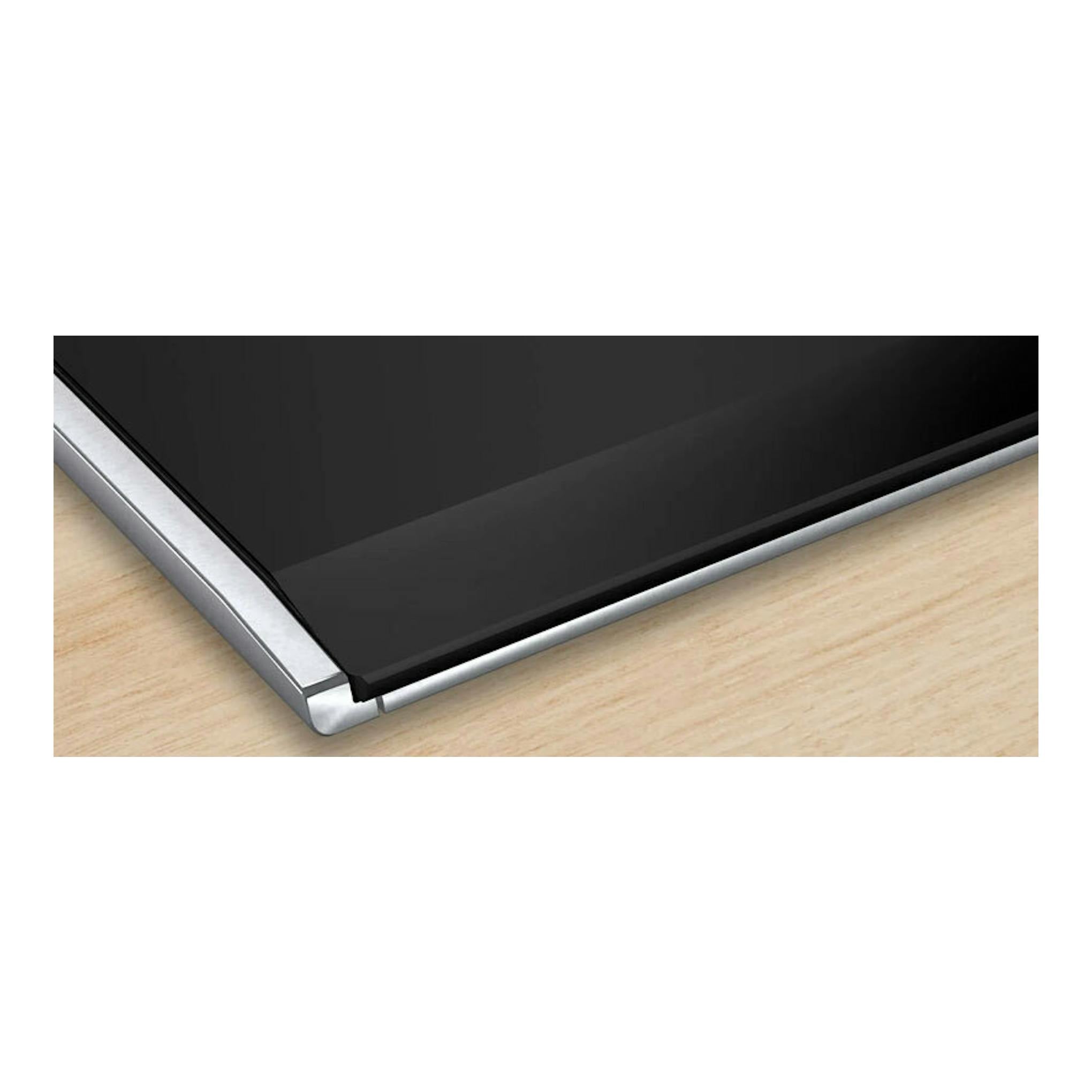 Placa de inducción Bosch PXJ675HC1E negra, vista en ángulo con borde metálico sobre encimera de madera.